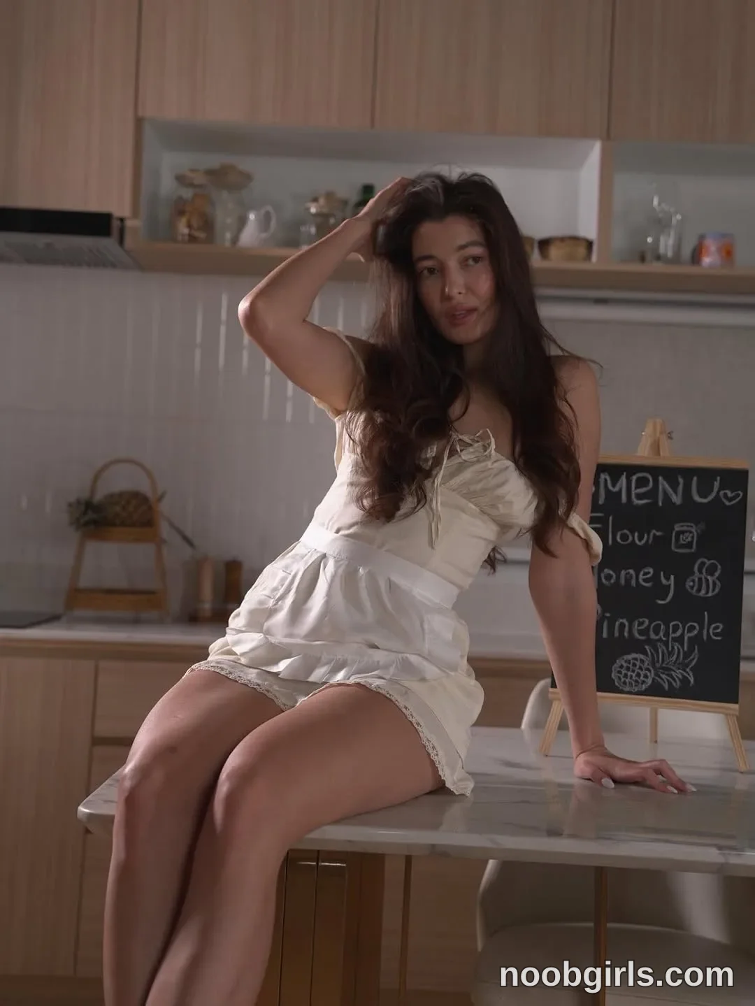 Arianna Sitting on the kitchen island with her legs hanging over the edge