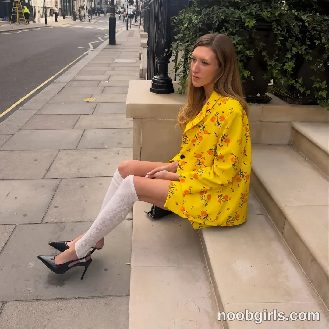 Addison Vodka Sitting sideways on a stone step with her legs extended toward the sidewalk