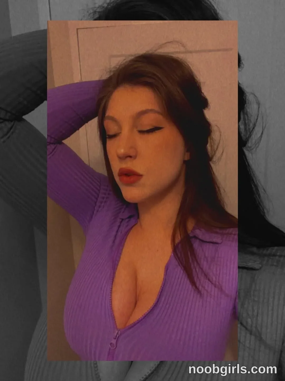 alexadream standing with eyes closed wearing purple ribbed long-sleeve zippered collared top against a wall and closed door