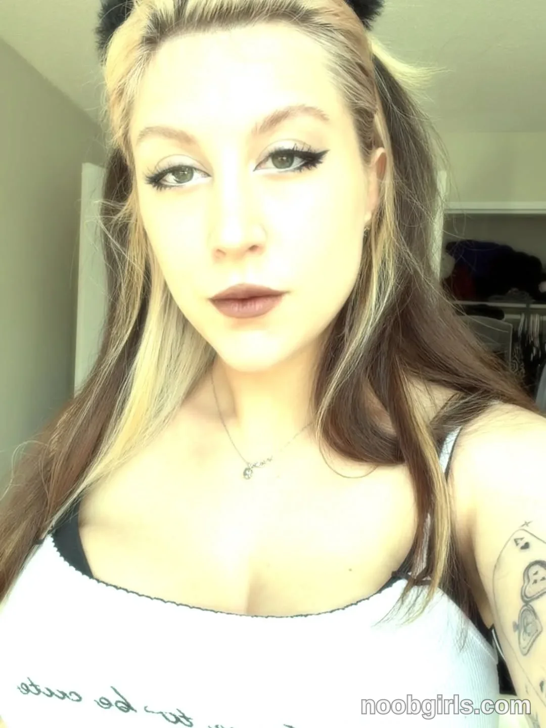 alexadream looking directly forward at the camera wearing white scoop-neck camisole top with black trim and script text