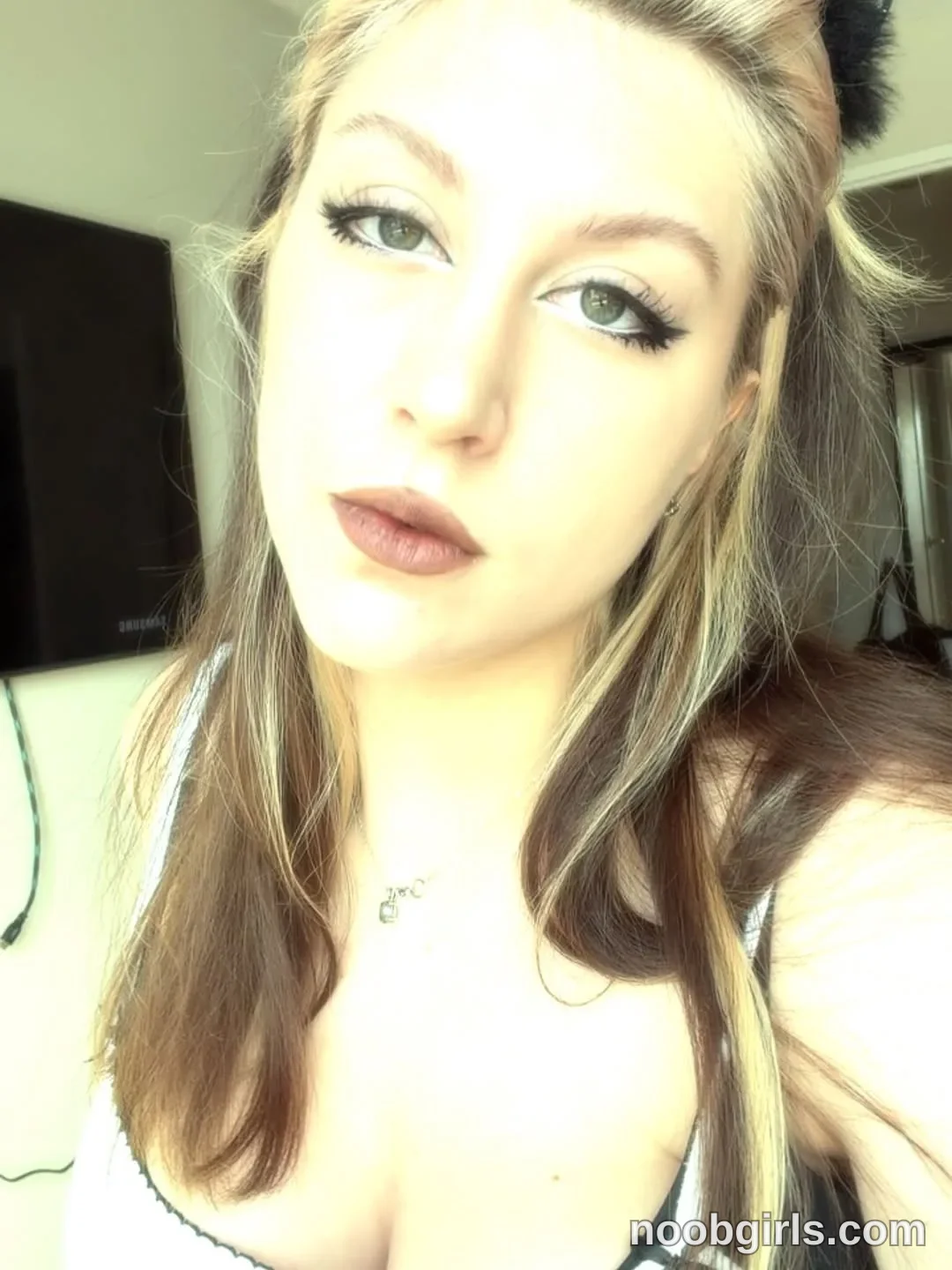 alexadream looking directly toward the camera for a close-up selfie portrait wearing white tank top or bra top with dark trim