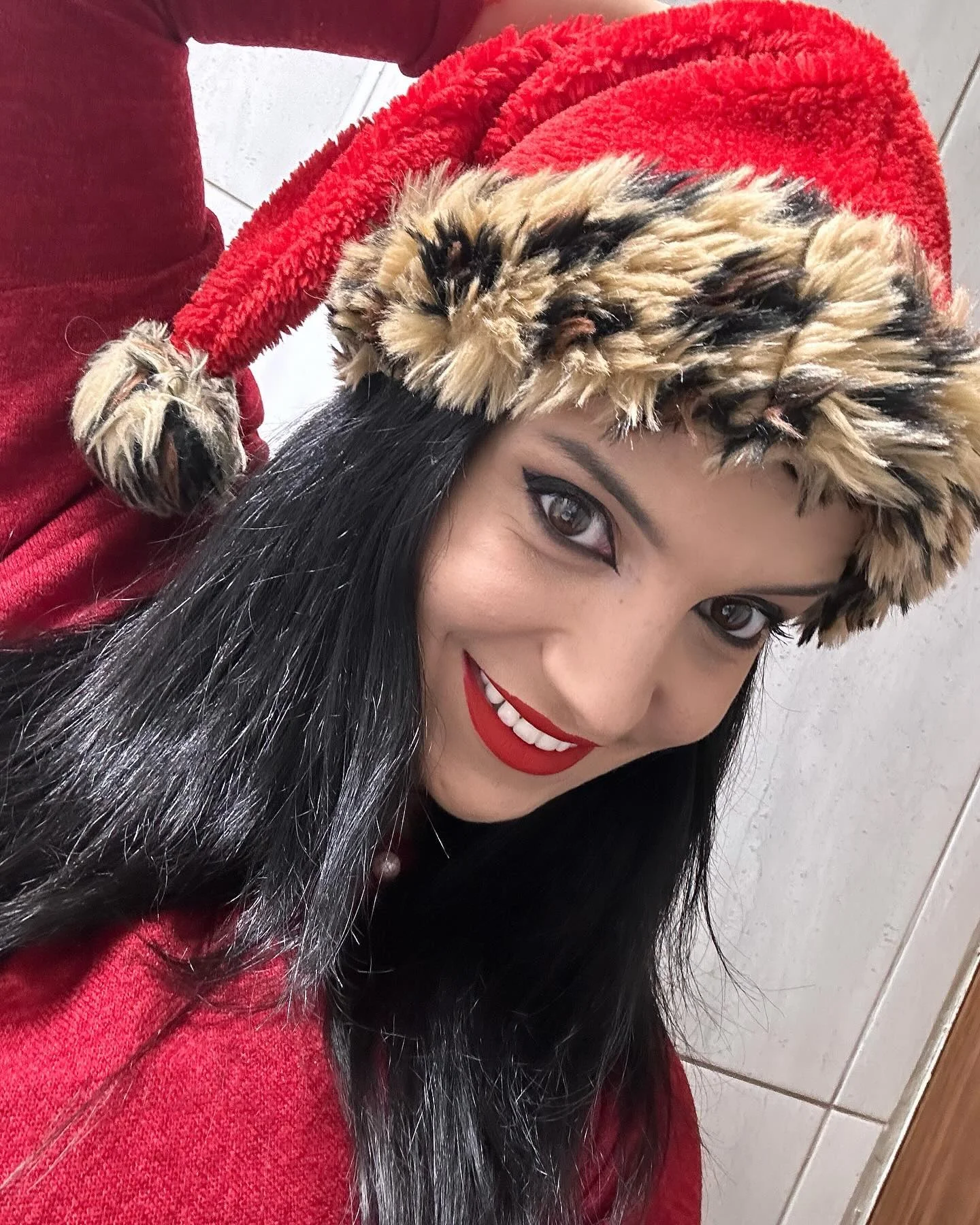 anaworld69 smiling at the camera wearing red Santa hat with leopard trim
