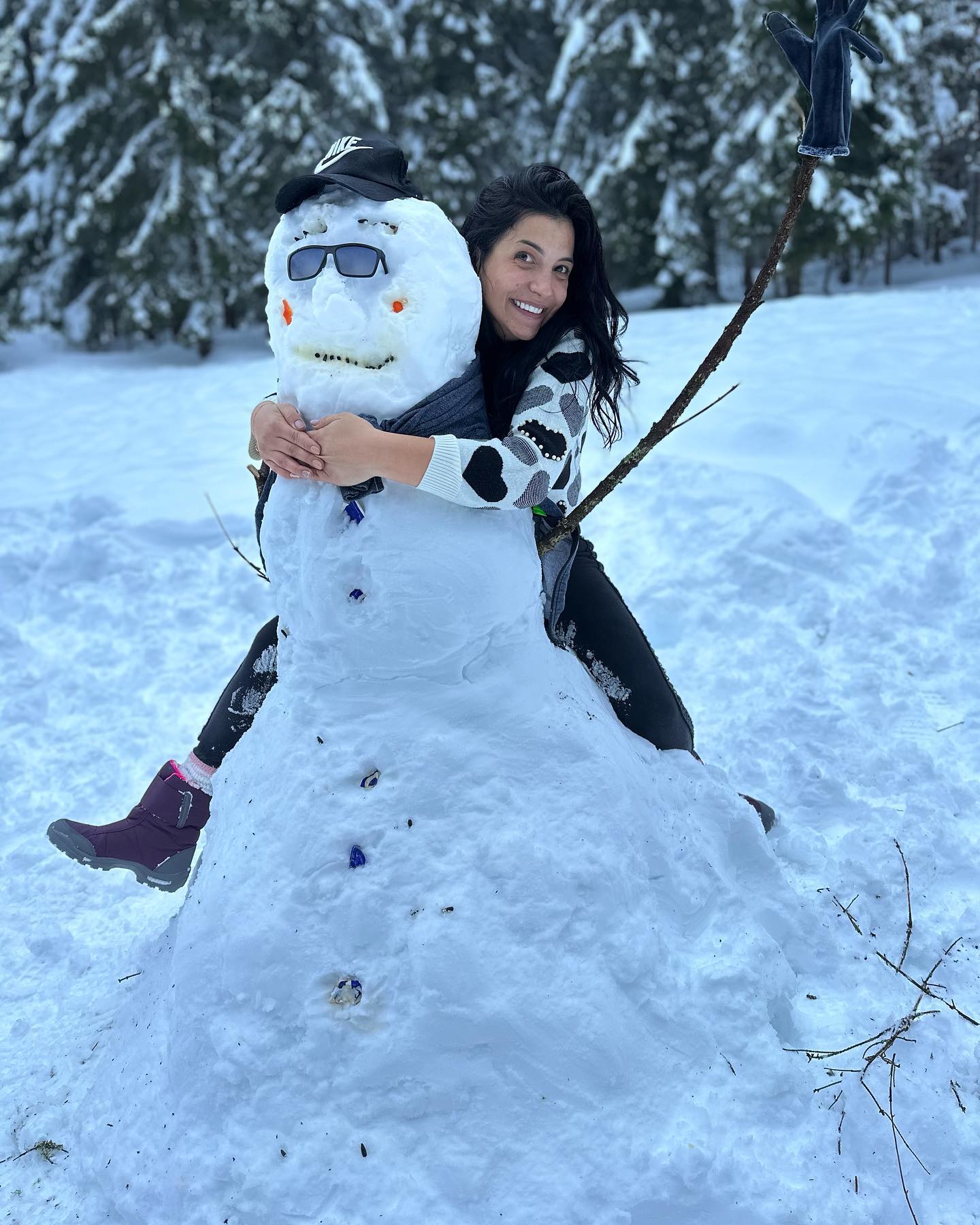 anaworld69 hugging a snowman wearing black and white patterned sweater in snowy outdoors
