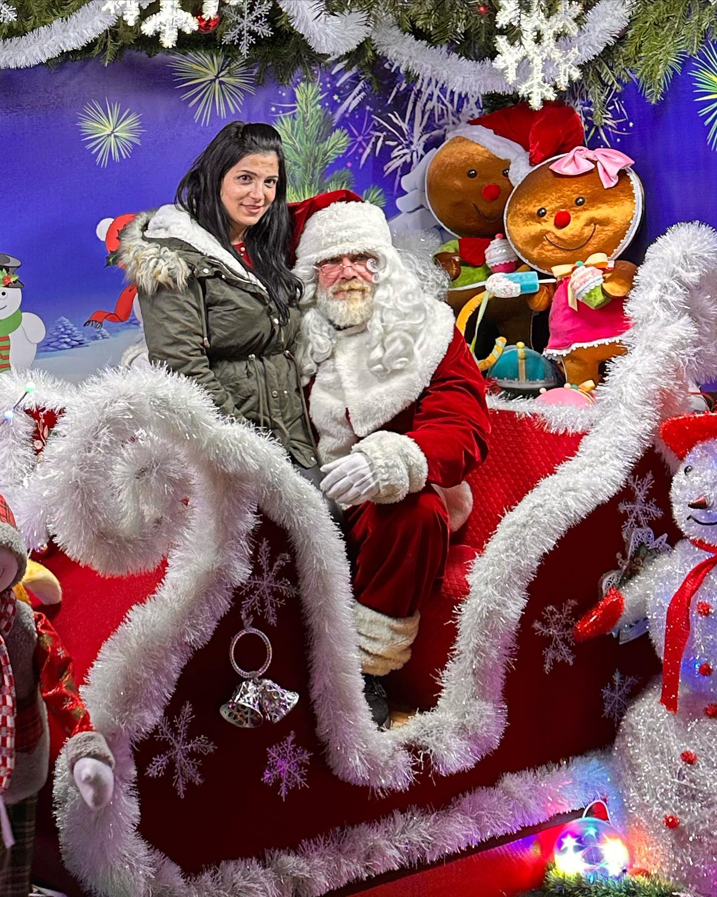 anaworld69 sitting in a decorated sleigh posing for a photo wearing olive green parka with fur-lined hood