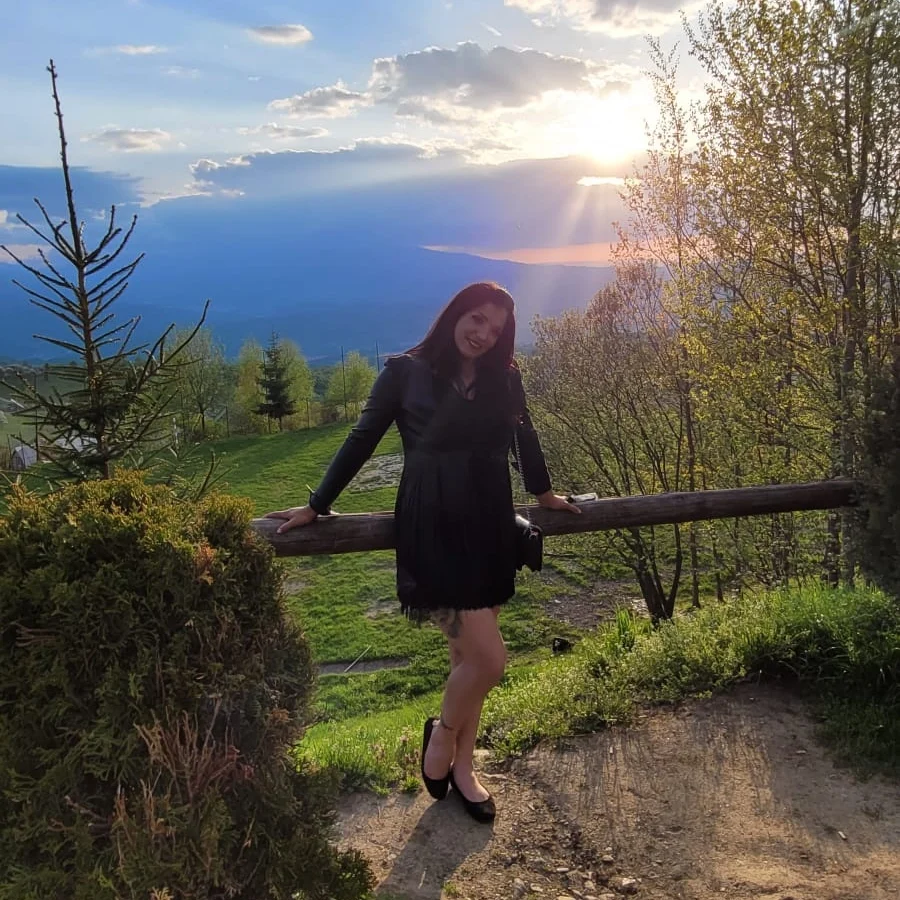 anaworld69 leaning on a wooden railing wearing black long-sleeved dress in scenic overlook