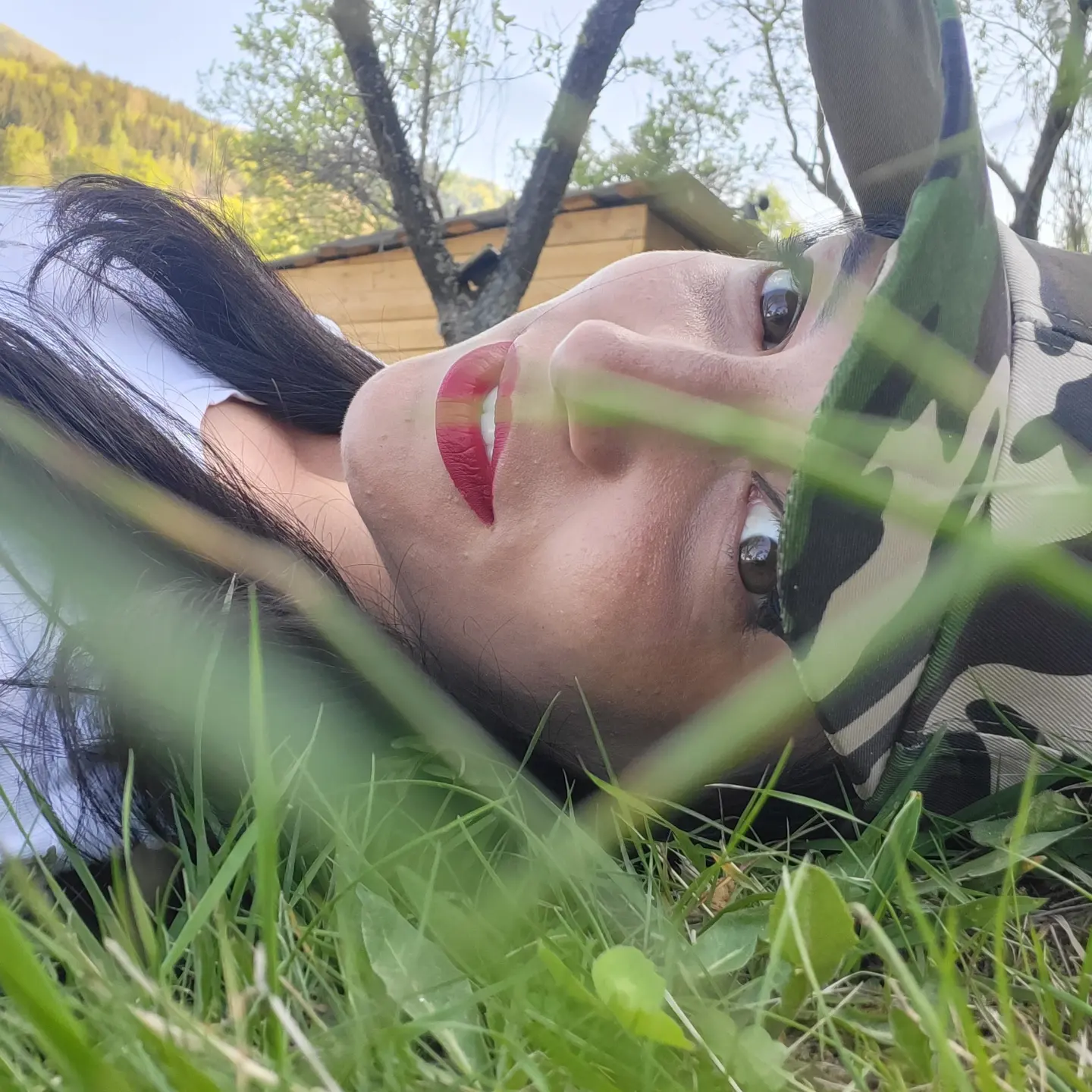 anaworld69 lying on grass wearing camouflage cap in grassy outdoors