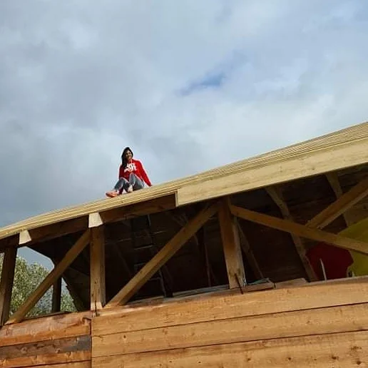 anaworld69 sitting on roof wearing red hoodie in wooden structure outdoors