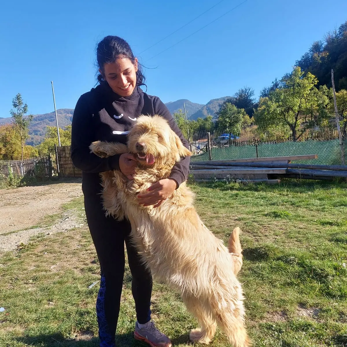 anaworld69 holding large dog wearing black hoodie in yard