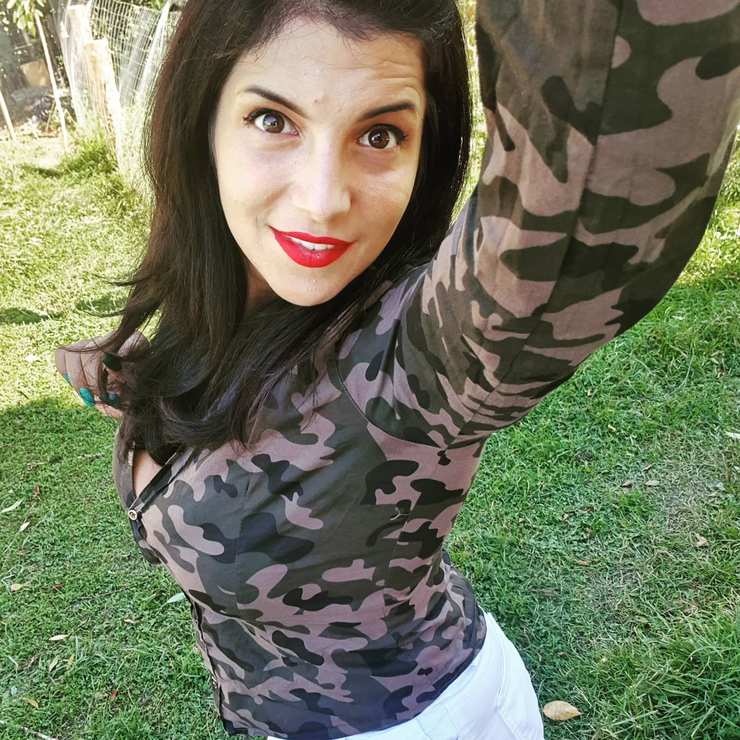 anaworld69 taking a selfie wearing camouflage long-sleeve shirt in grassy yard