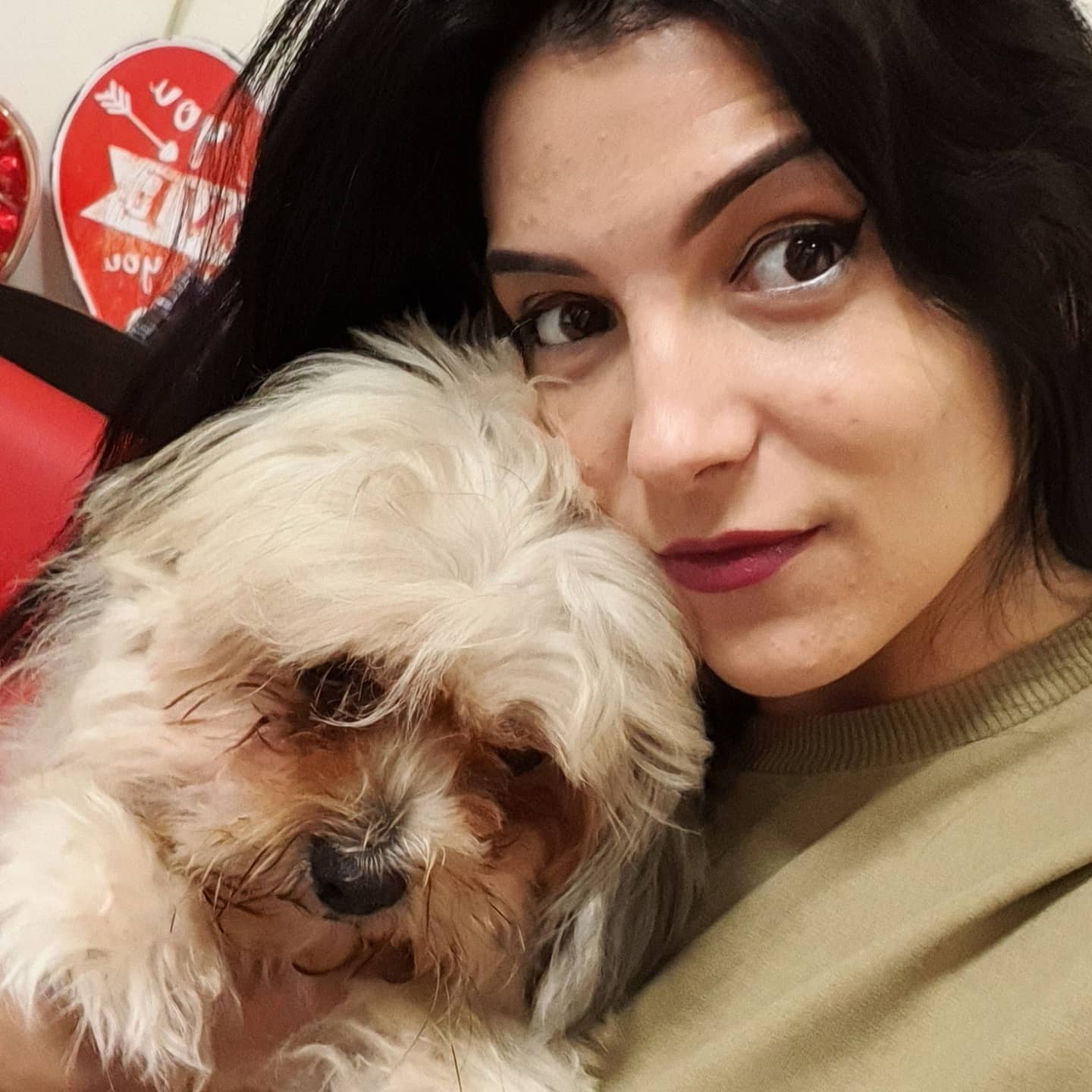 anaworld69 holding a small dog wearing green crewneck shirt