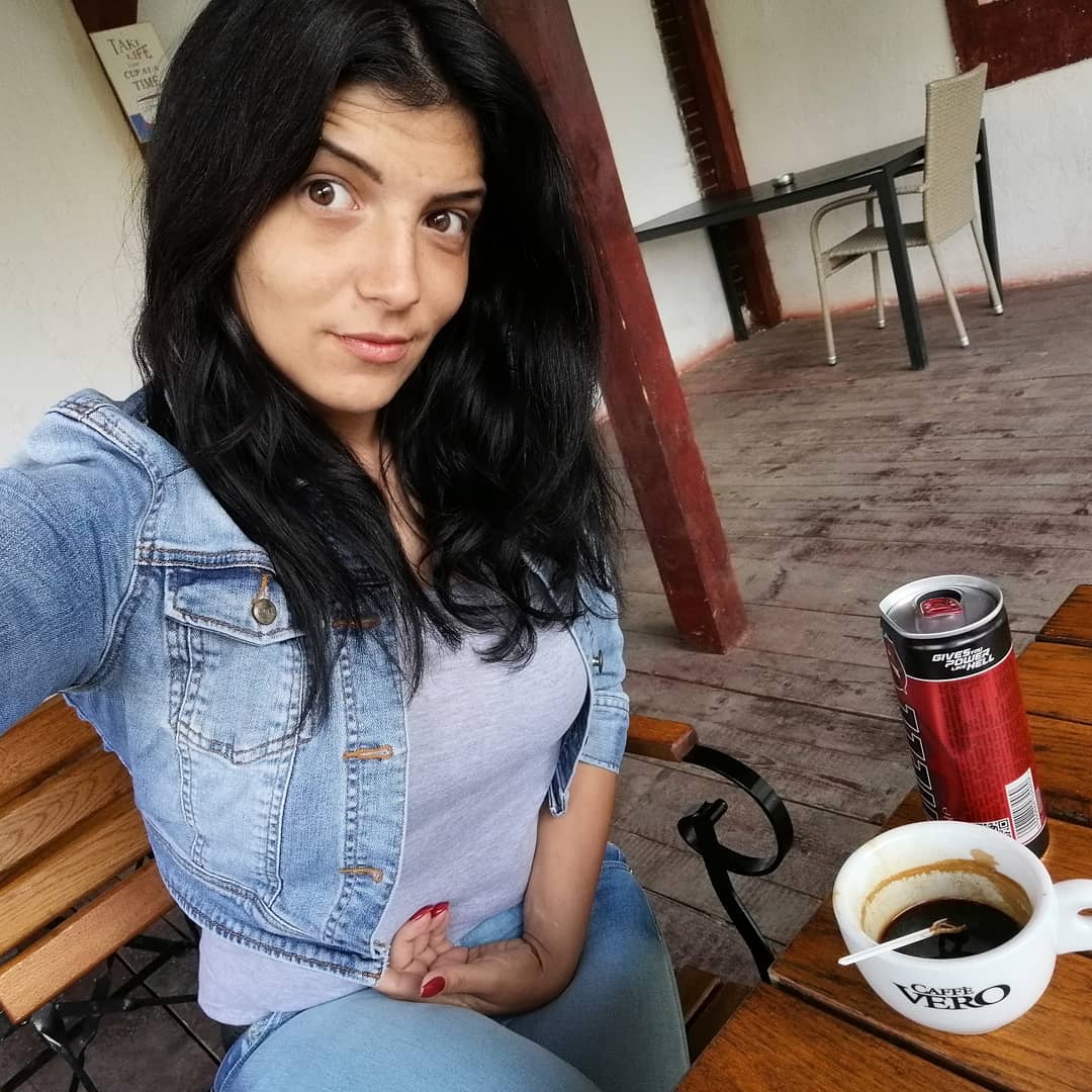 anaworld69 sitting at a table wearing blue denim jacket in cafe patio
