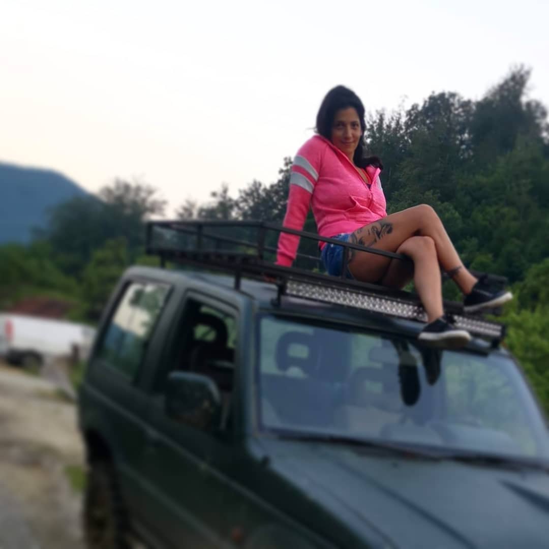 anaworld69 sitting on roof rack wearing pink jacket in with trees