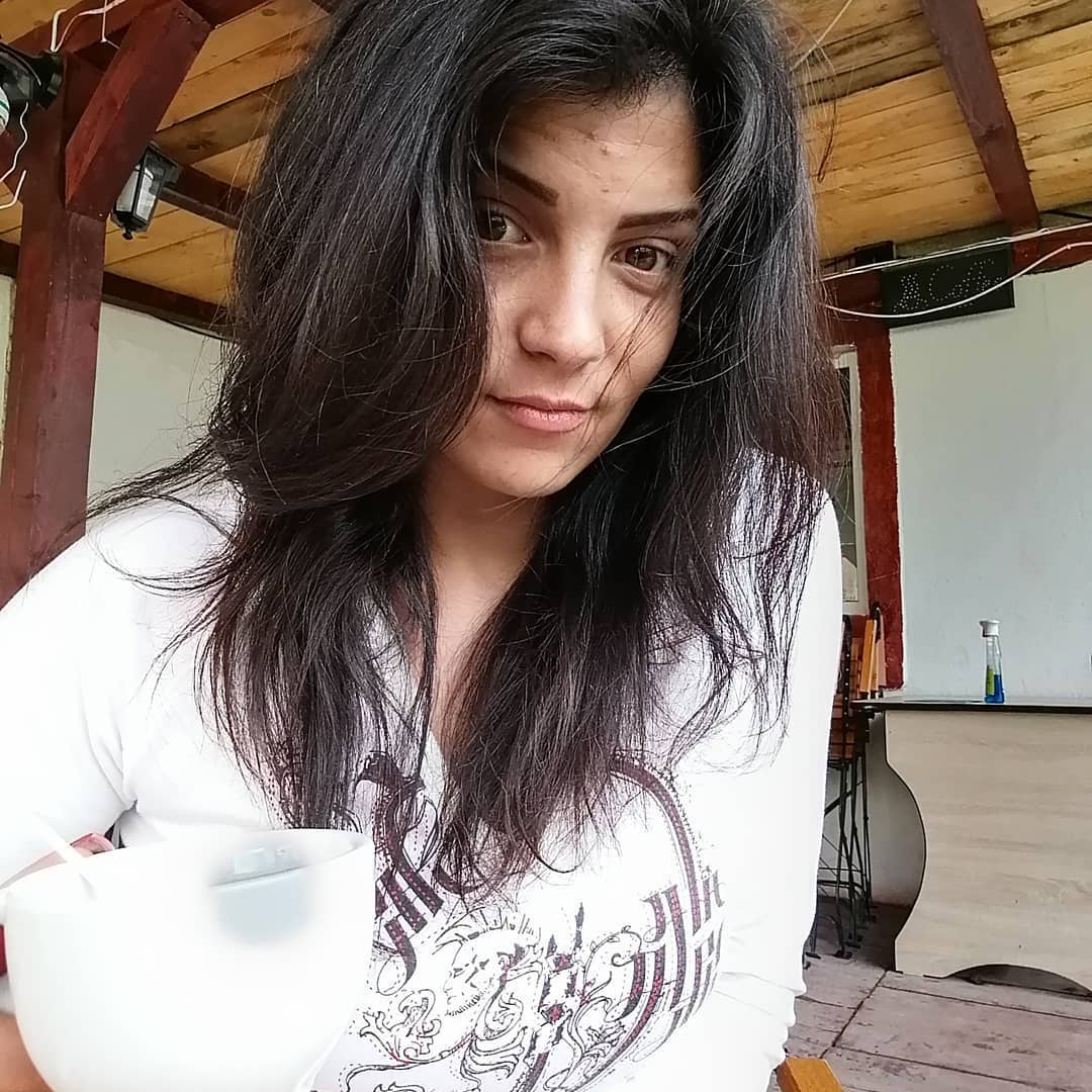 anaworld69 holding cup wearing white graphic shirt in covered patio