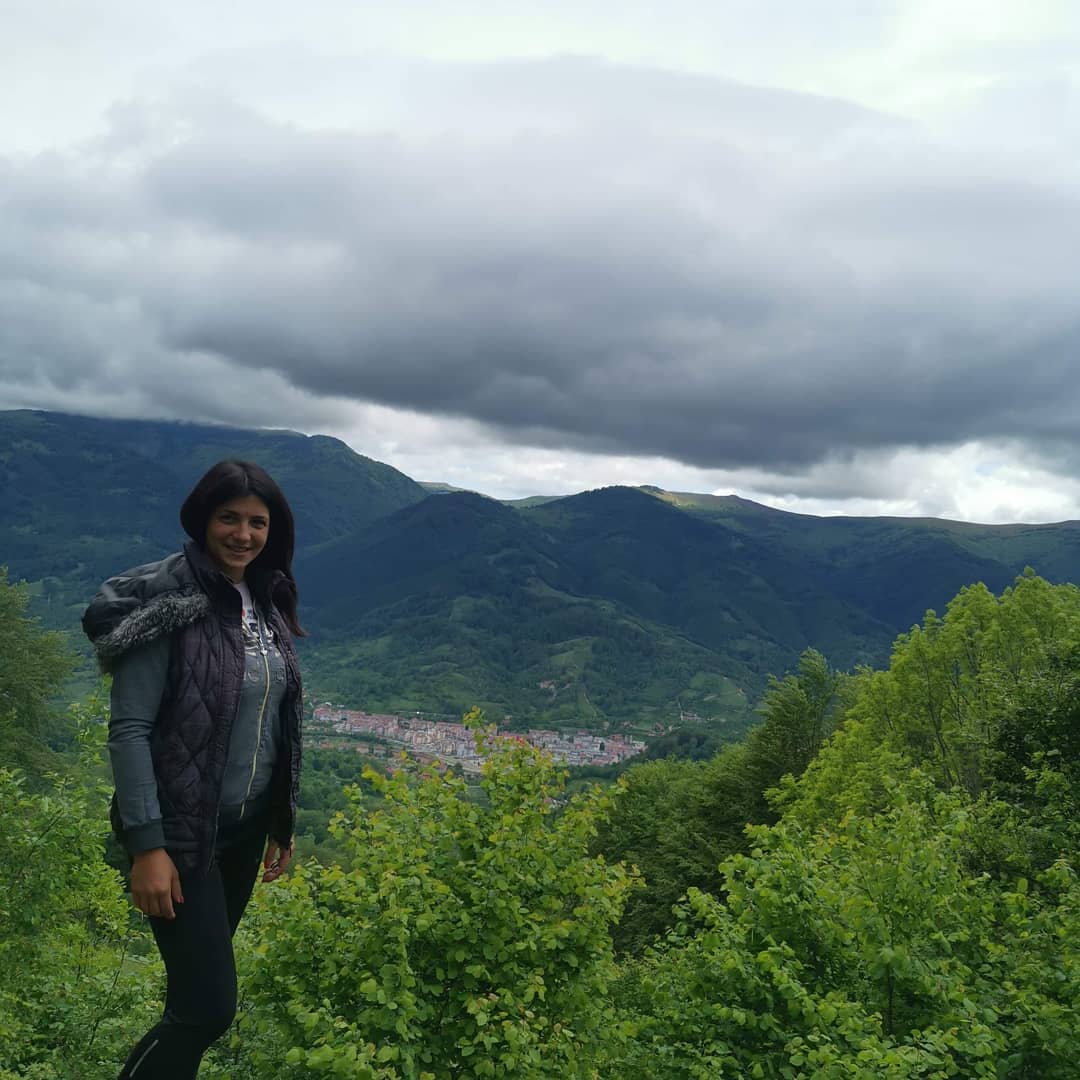 anaworld69 standing outdoors wearing dark hooded vest in mountain overlook