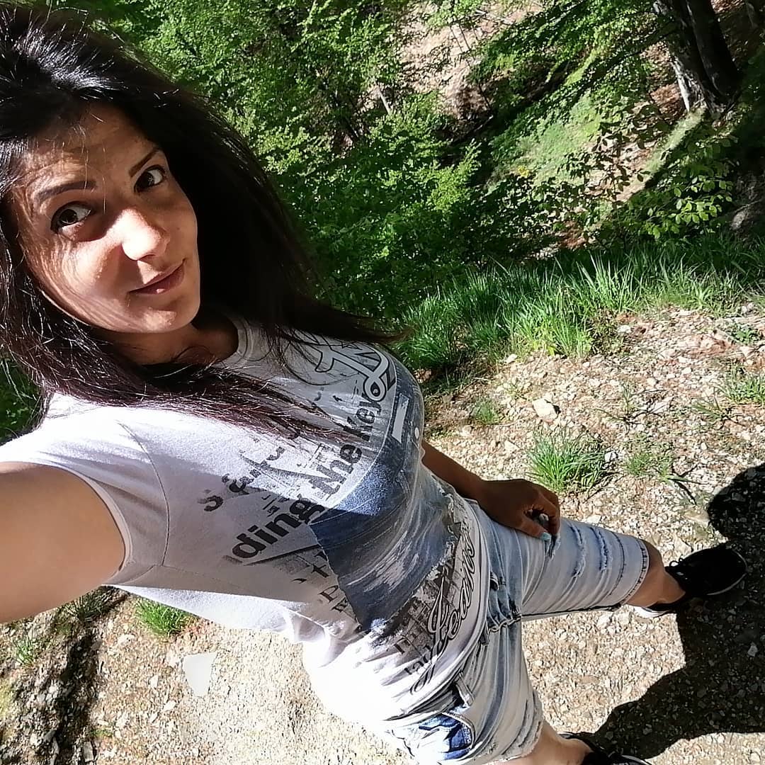 anaworld69 taking a selfie wearing white graphic t-shirt in forest trail