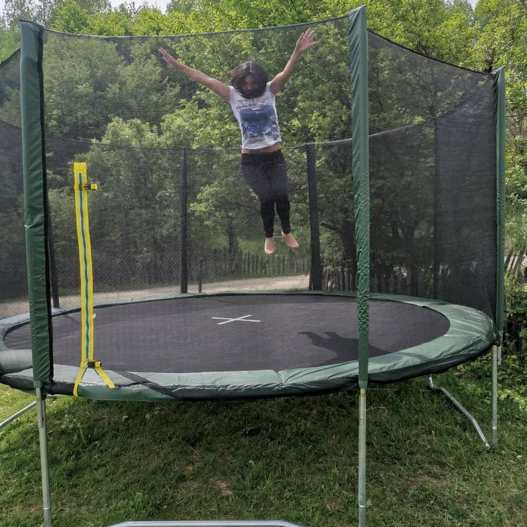anaworld69 jumping on a trampoline wearing white graphic t-shirt in yard