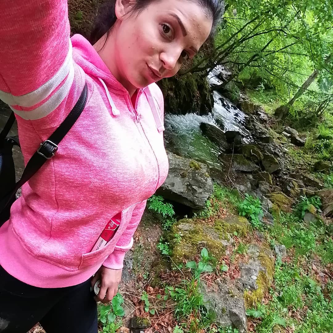 anaworld69 taking a selfie wearing pink hoodie in forest stream
