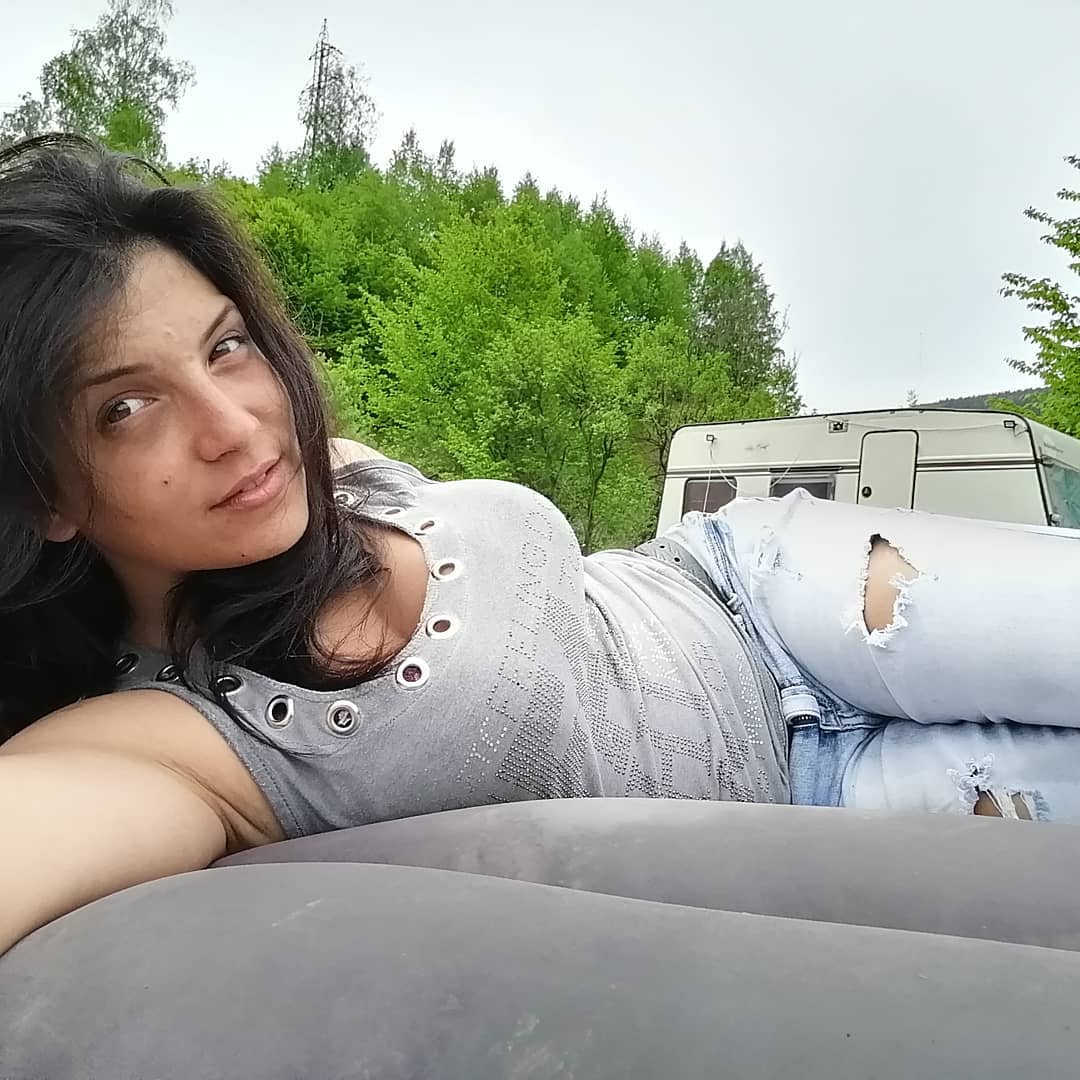 anaworld69 lying on air mattress wearing grey tank top near camper
