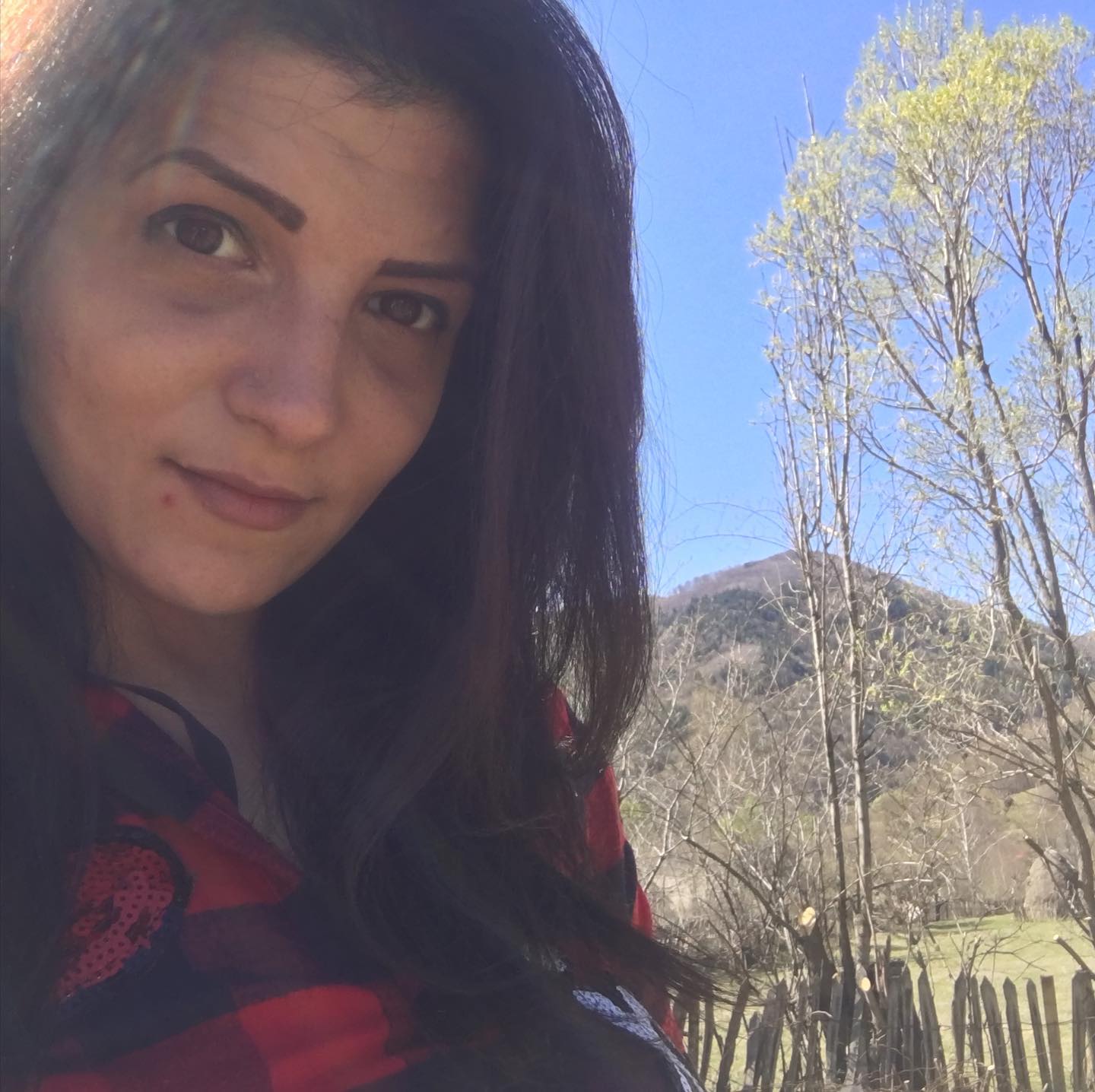 anaworld69 taking a selfie wearing red and black plaid top in countryside