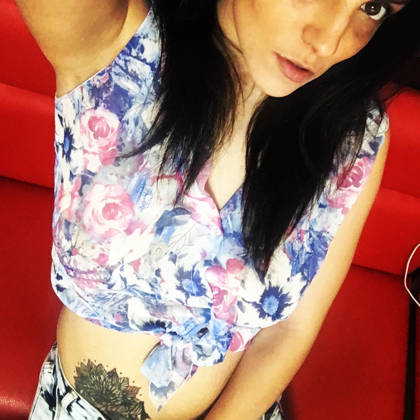 anaworld69 posing for selfie wearing floral print sleeveless top on red couch