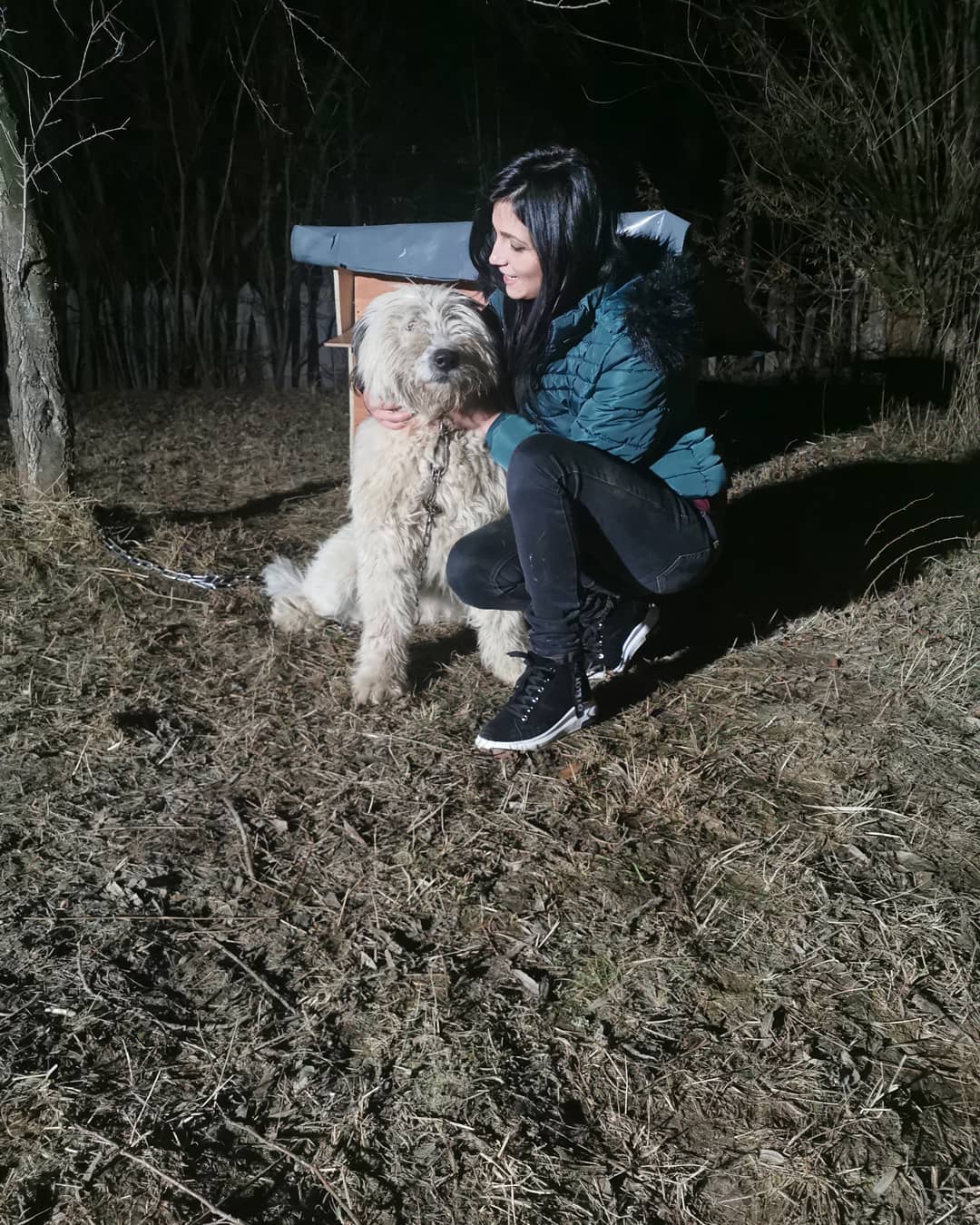 anaworld69 crouching beside a dog wearing teal puffer jacket at night