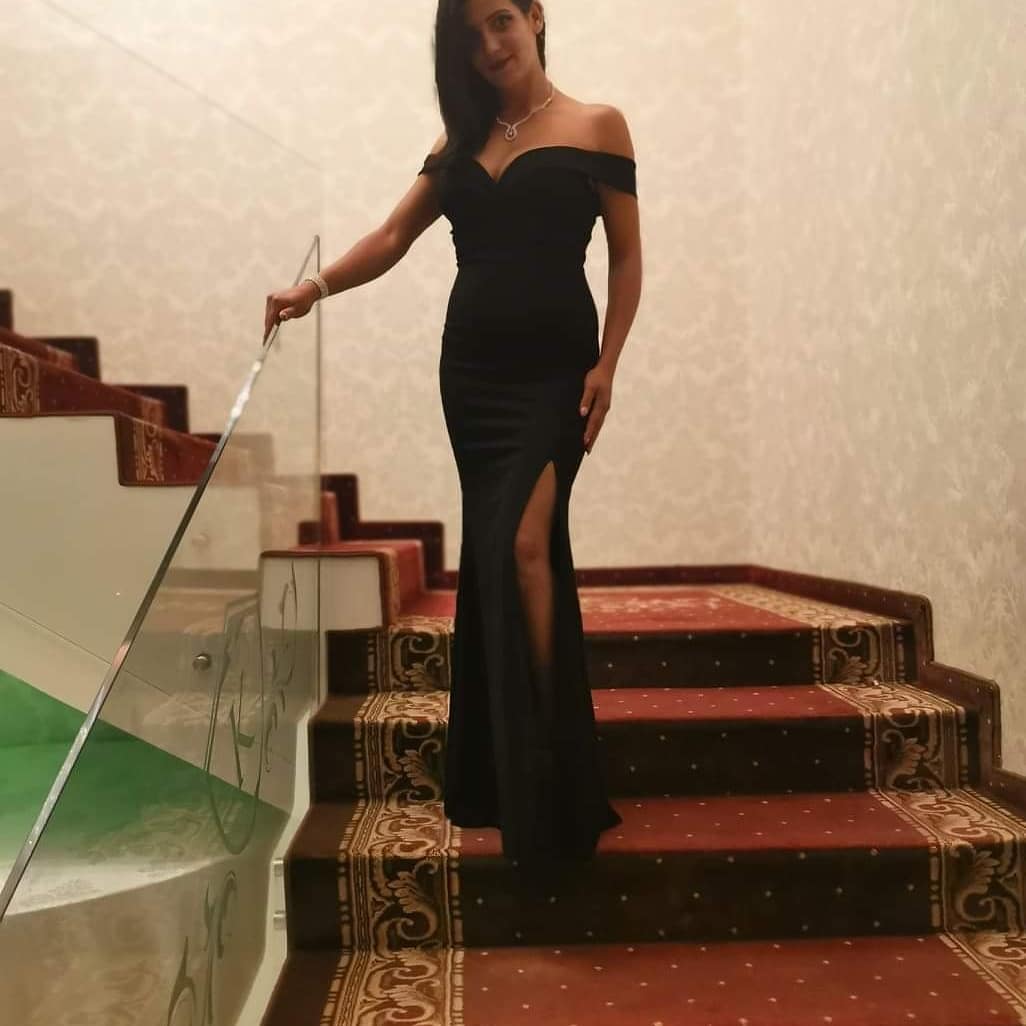 anaworld69 standing on stairs wearing black off-shoulder dress in staircase