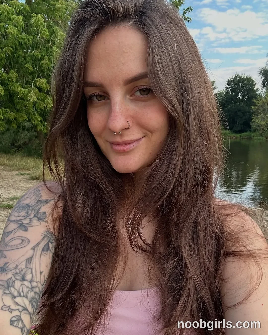 Alice Facing the camera with her head slightly tilted wearing Pink top beside a body of water