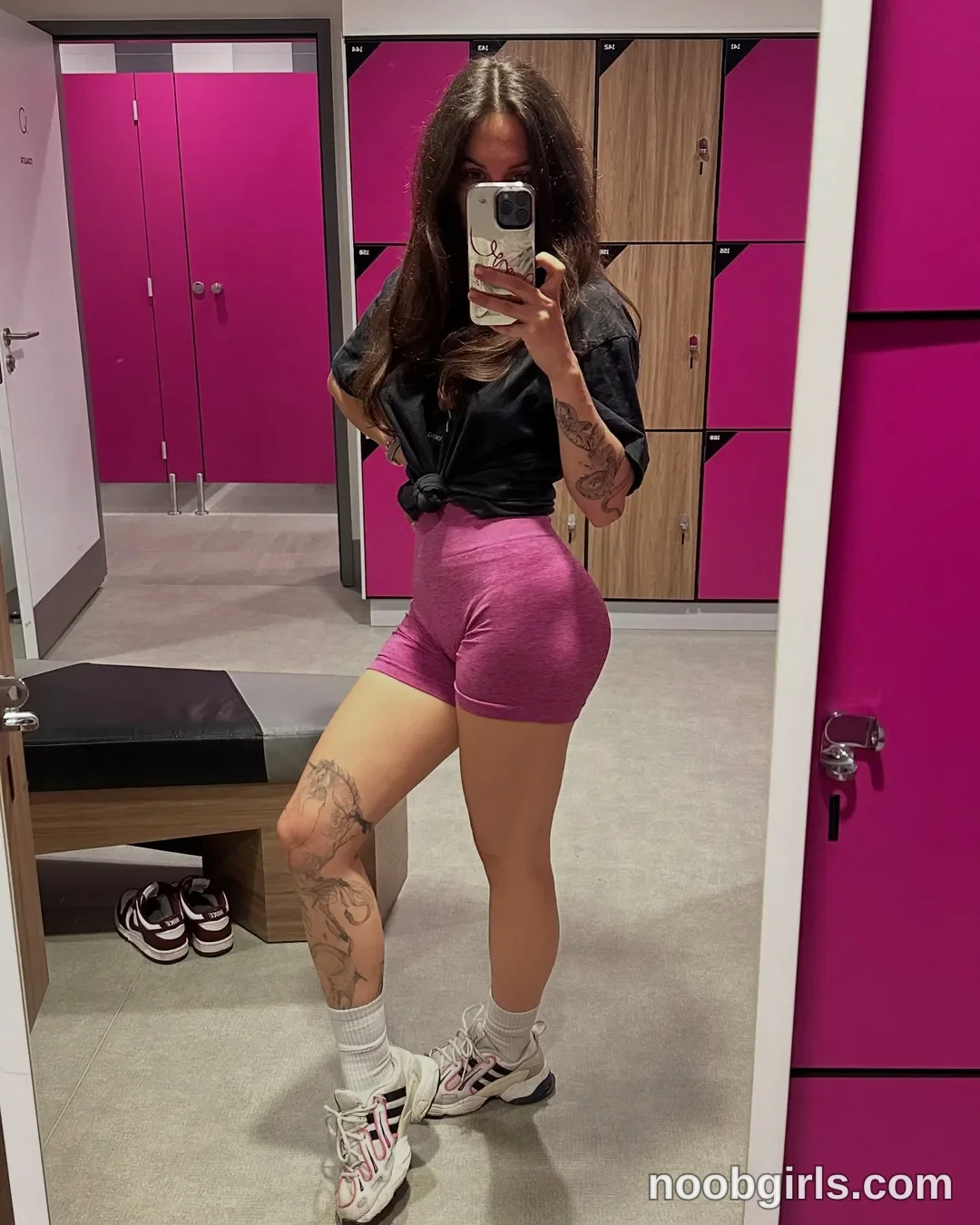 Alice Standing in front of a mirror wearing Black short-sleeved top tied at the waist in changing room