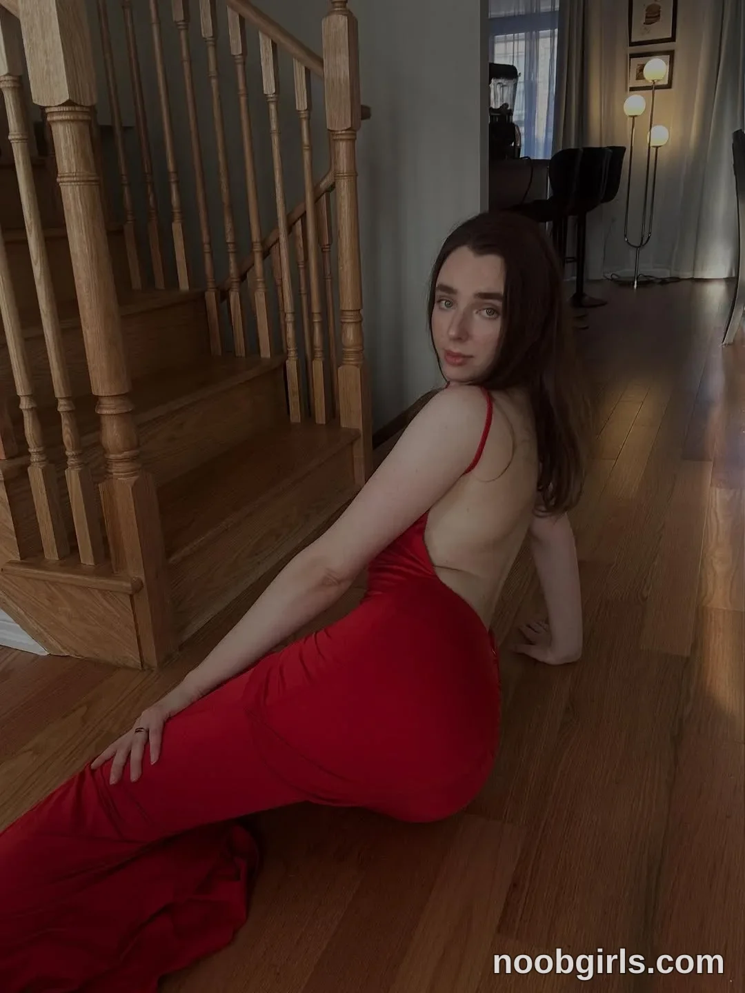 Anna sitting or leaning on a wooden floor next to a staircase with one arm supporting herself