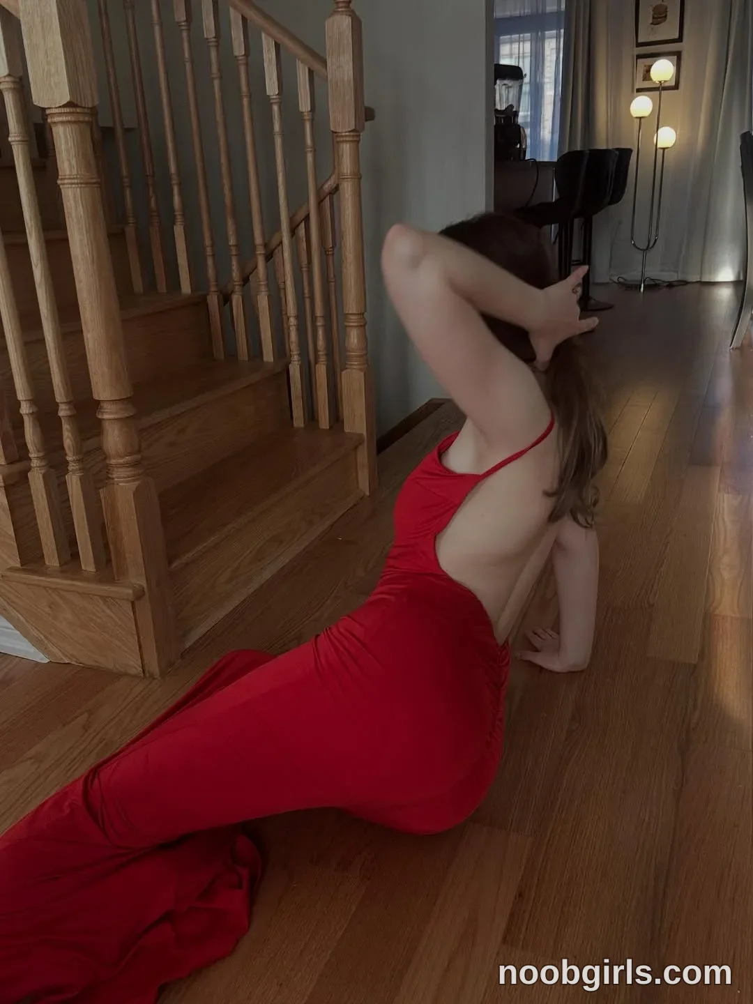 Anna sitting on hardwood floor leaning back on one hand with the other hand touching the back of her head