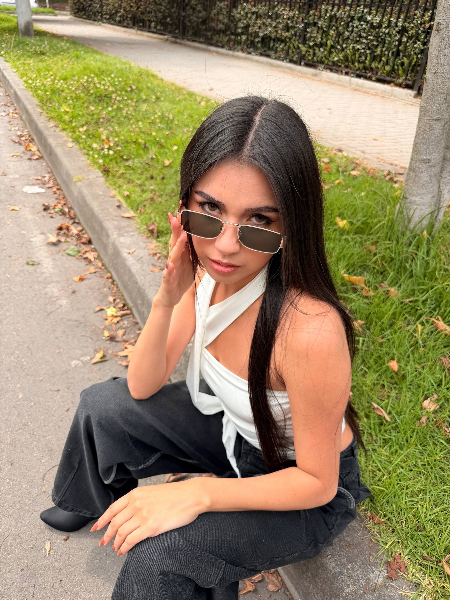 ashley_jones9 crouching on the curb wearing white halter top in sidewalk by lawn