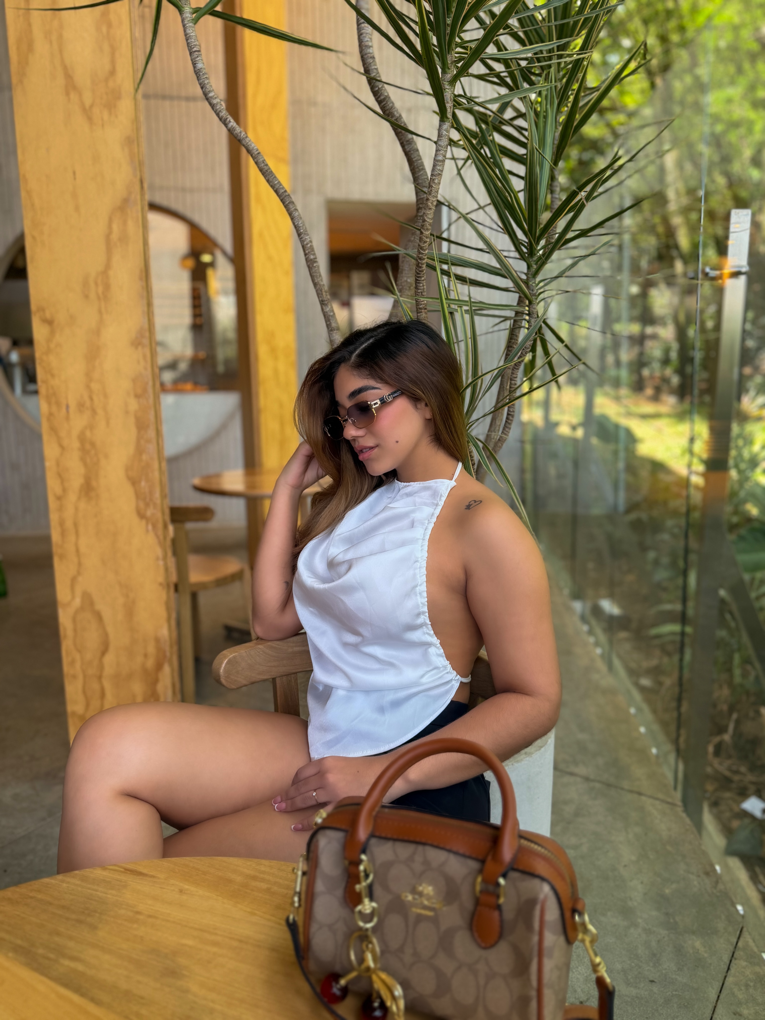 ashley_ospino sitting at a table wearing white halter top in cafe