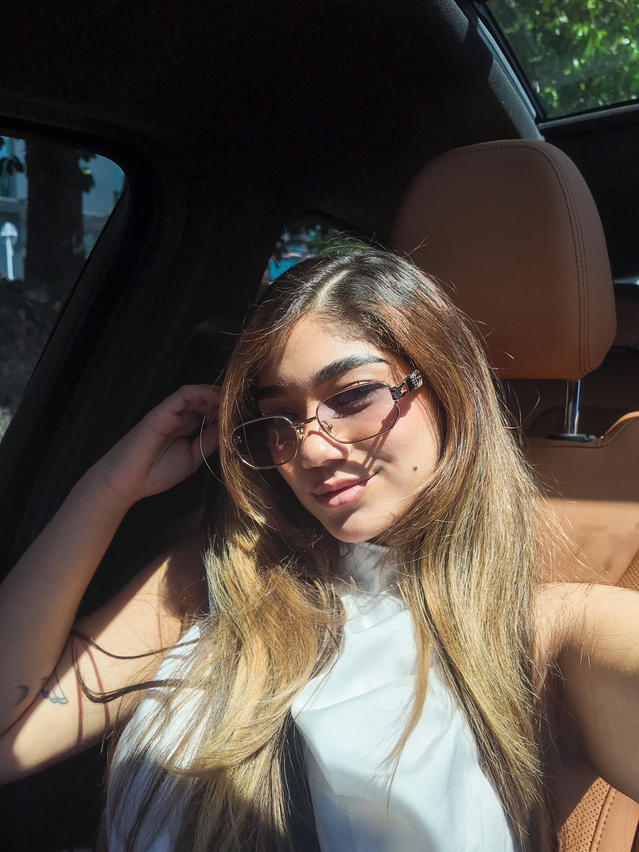 ashley_ospino taking selfie wearing white sleeveless top in car interior