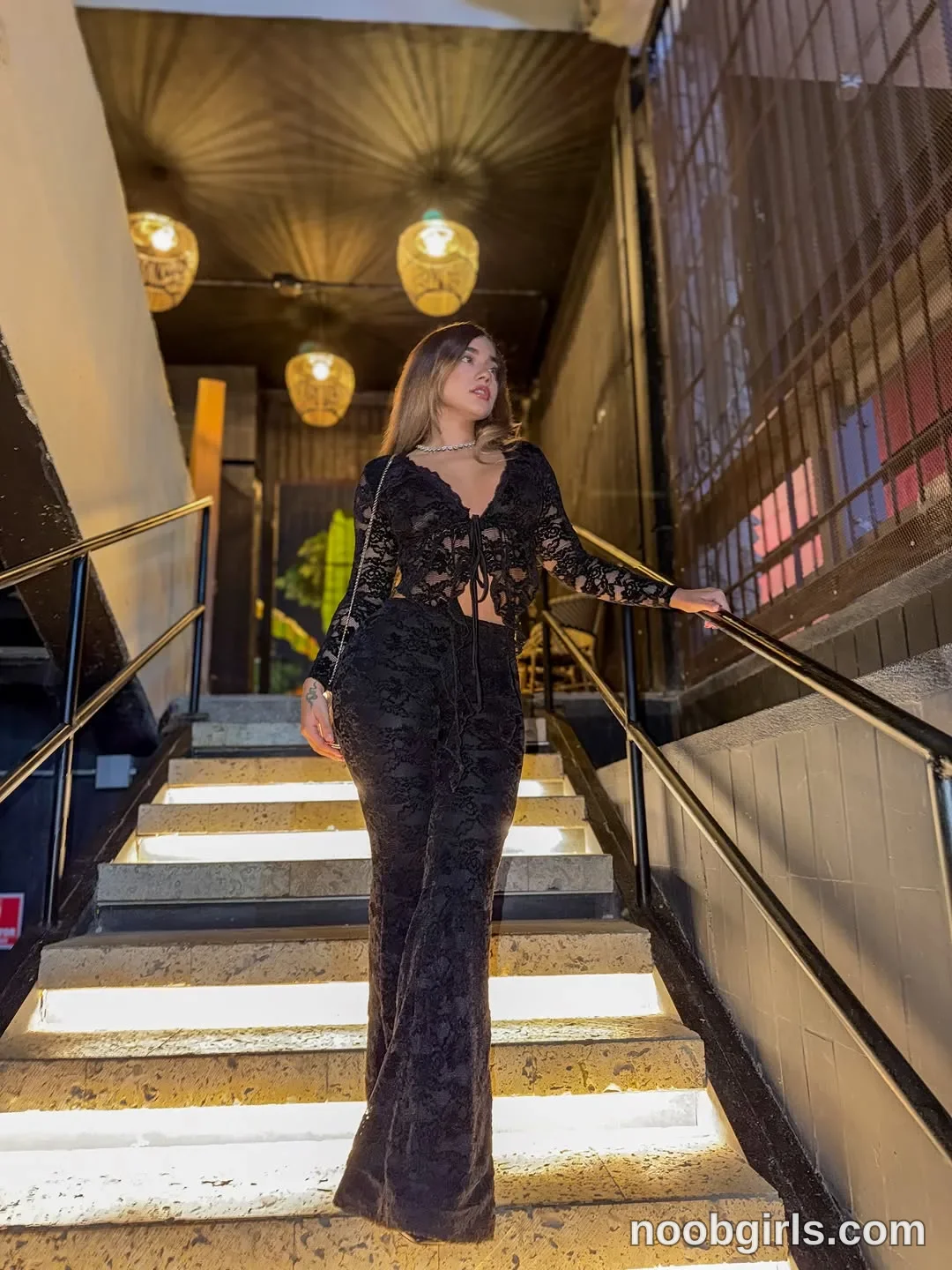 Ale standing on a flight of stairs with one hand resting on the metal handrail