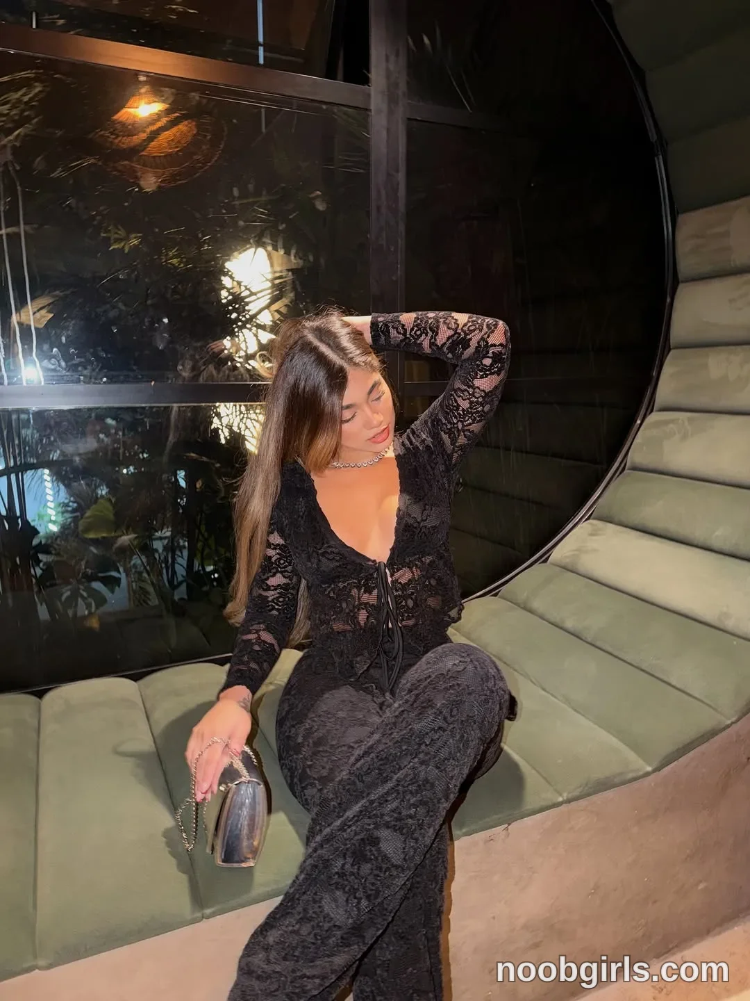 Ale sitting on a curved upholstered bench with legs crossed