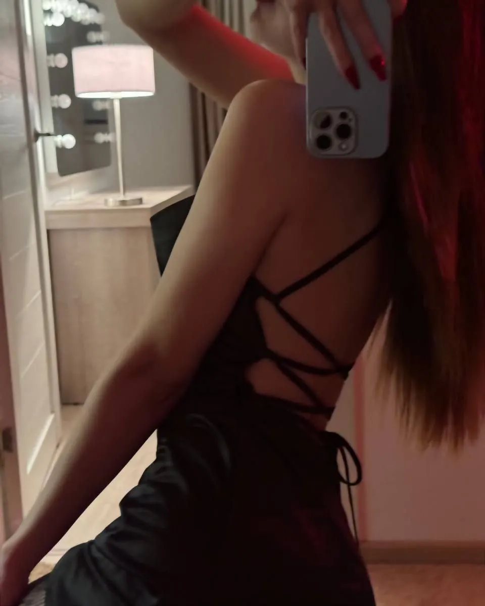 asuna_niiya taking a selfie wearing black backless dress in room