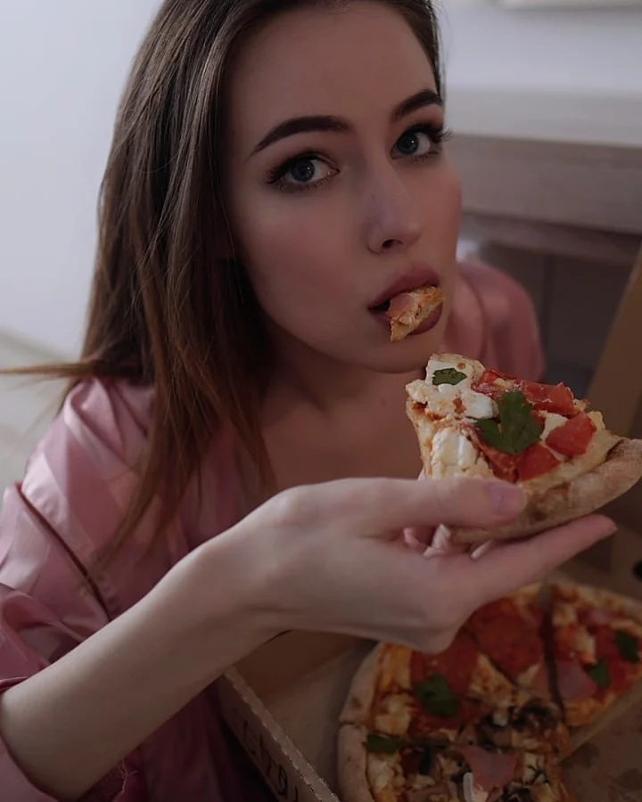asuna_niiya eating a slice of pizza wearing pink satin robe