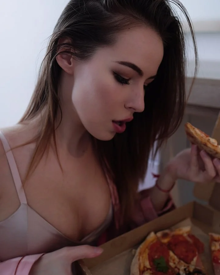 asuna_niiya holding pizza slice wearing light pink silk top