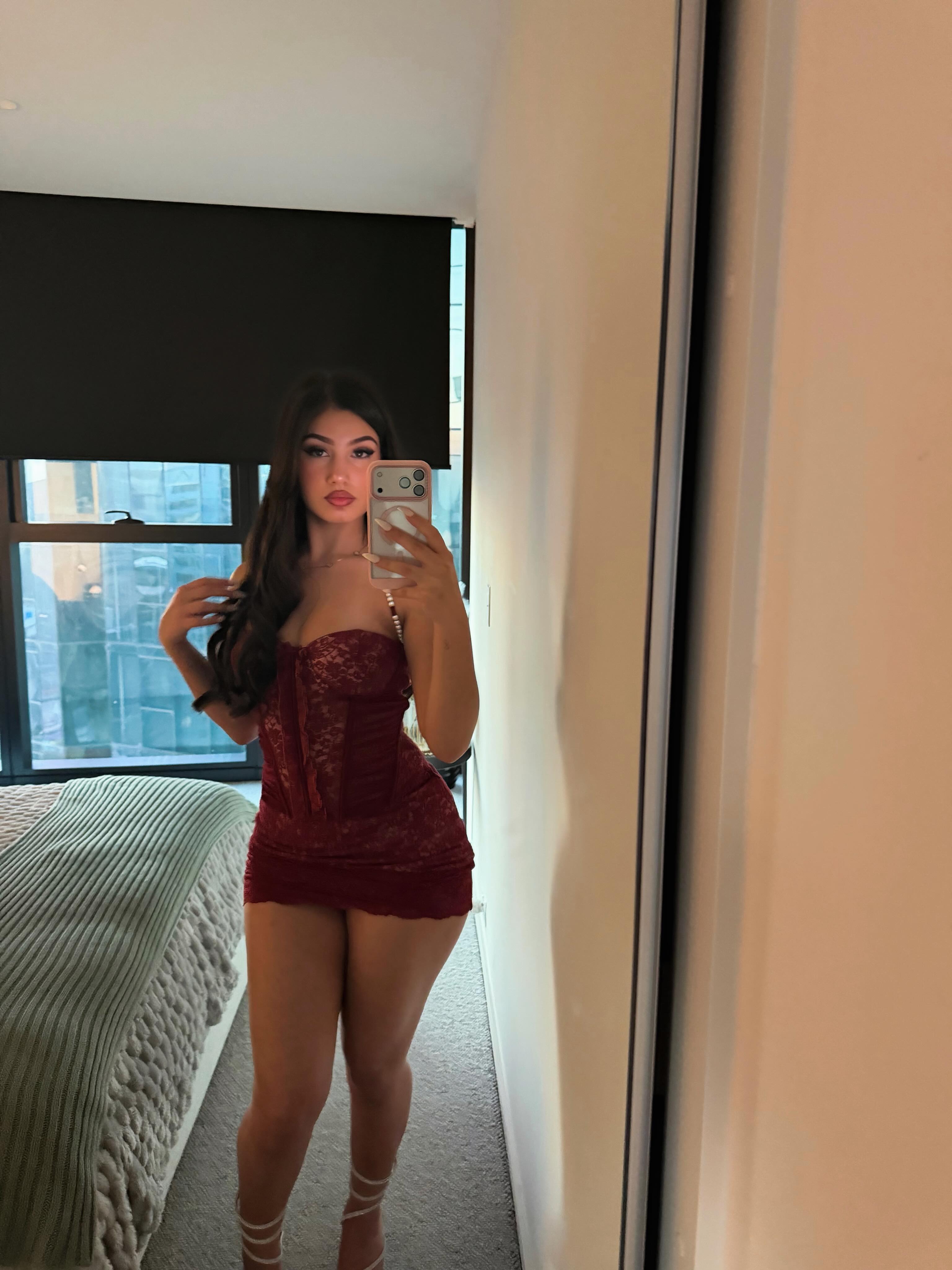 ava_delightt taking a mirror selfie wearing red lace dress in bedroom