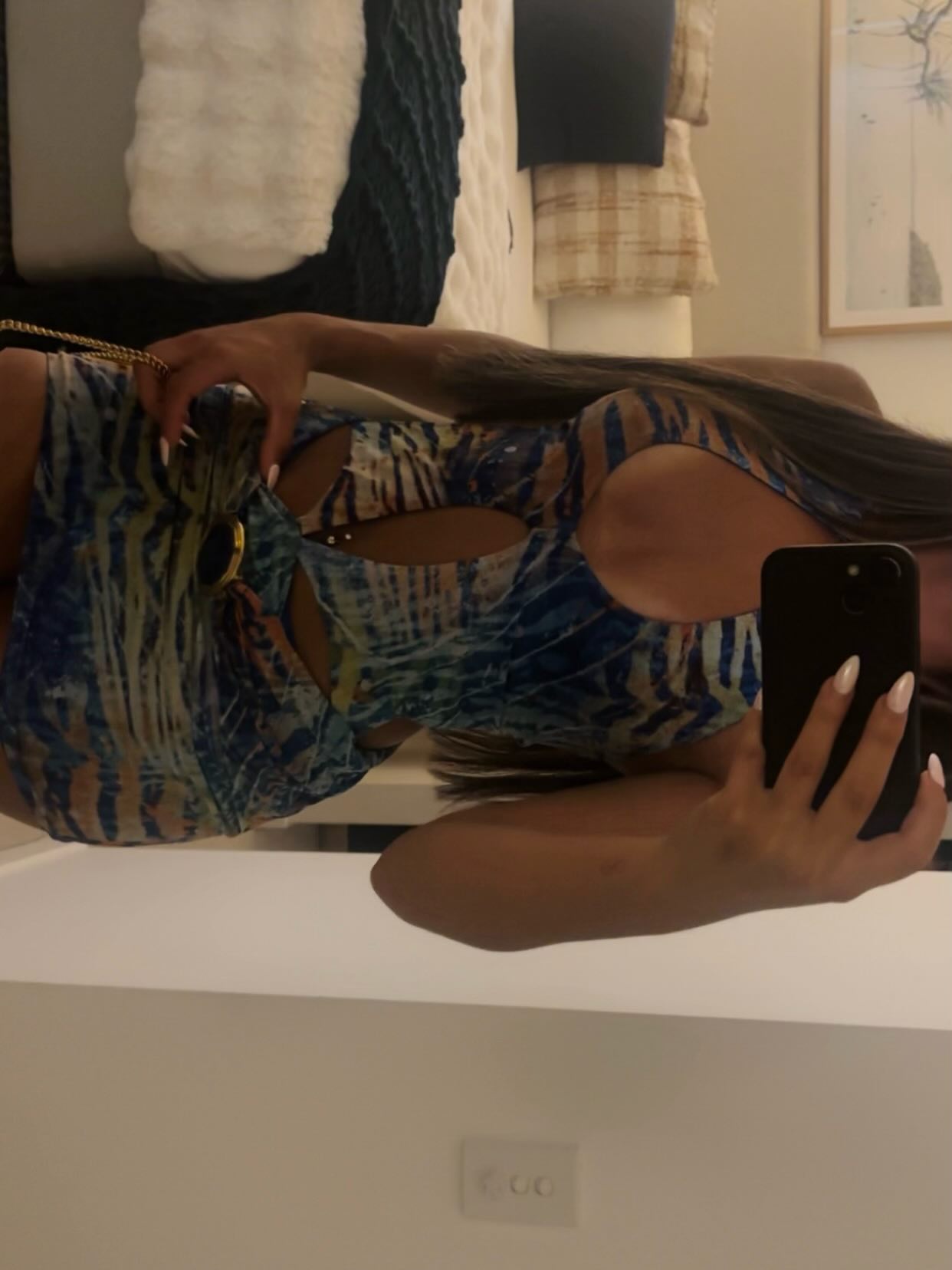 ava_delightt taking a mirror selfie wearing patterned blue cut-out dress in bedroom