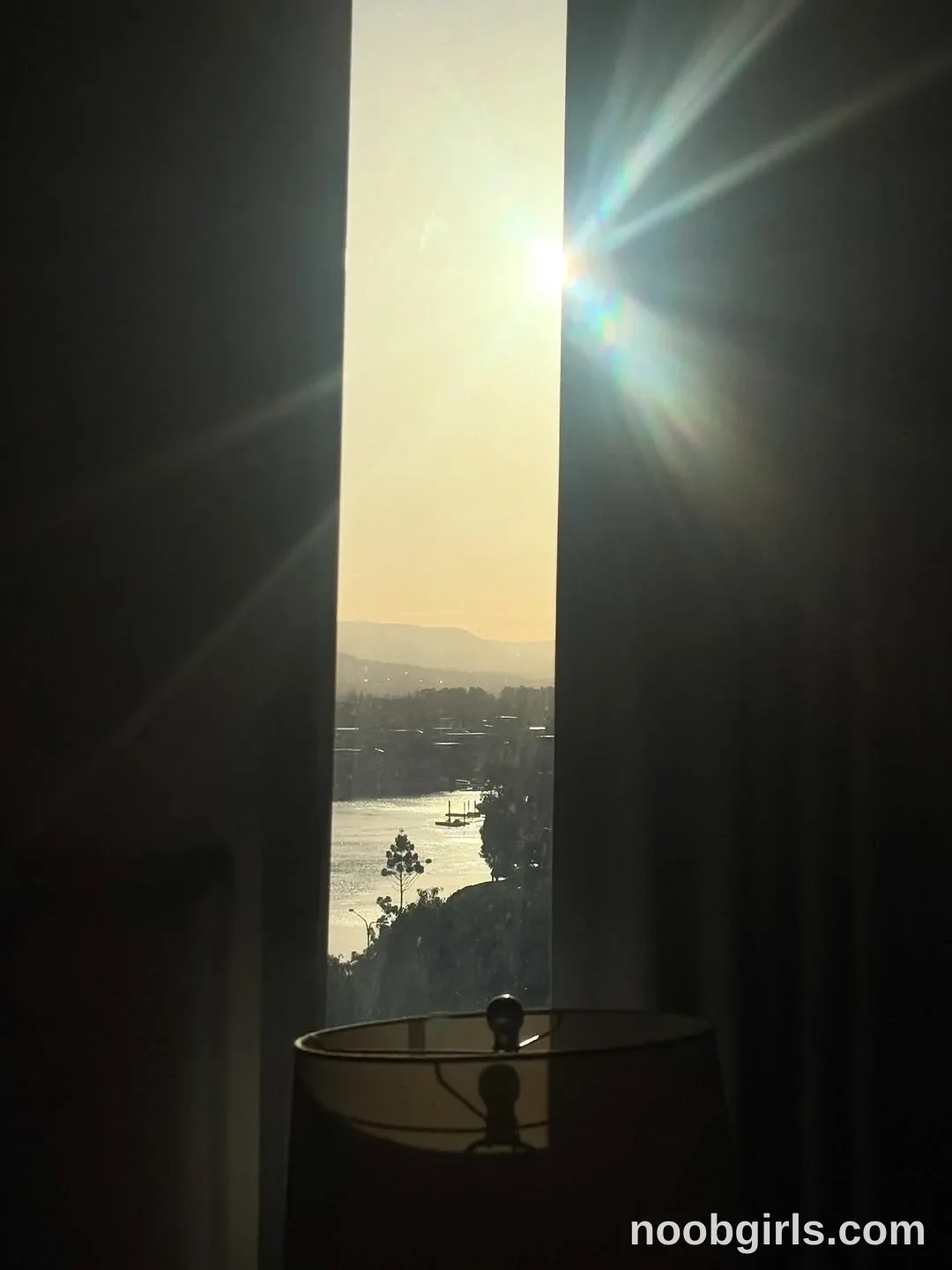 Ava No person is visible in room looking through a narrow gap between curtains toward a body of water