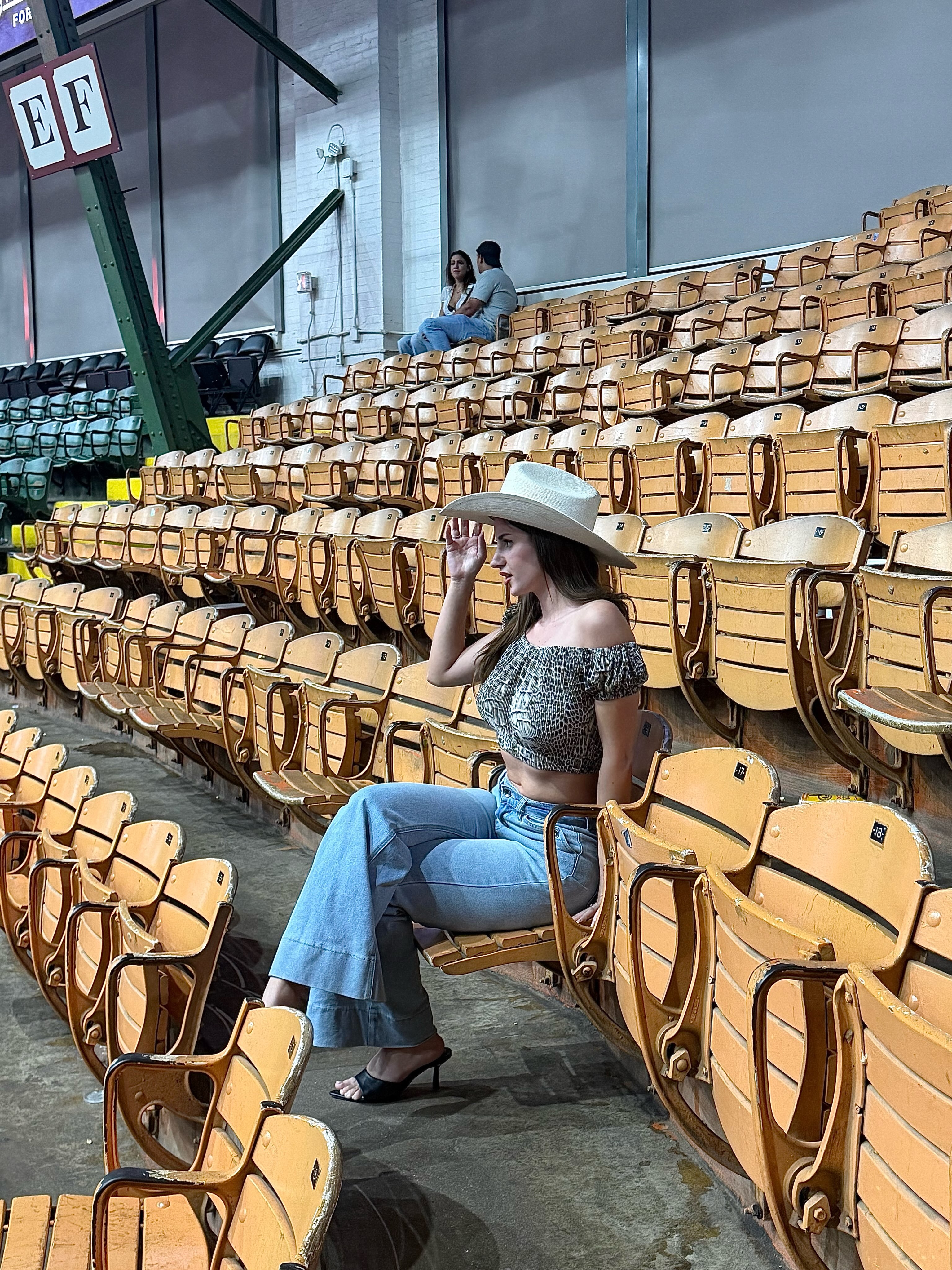 aviebby sitting in stadium seats wearing white cowboy hat in stadium seating