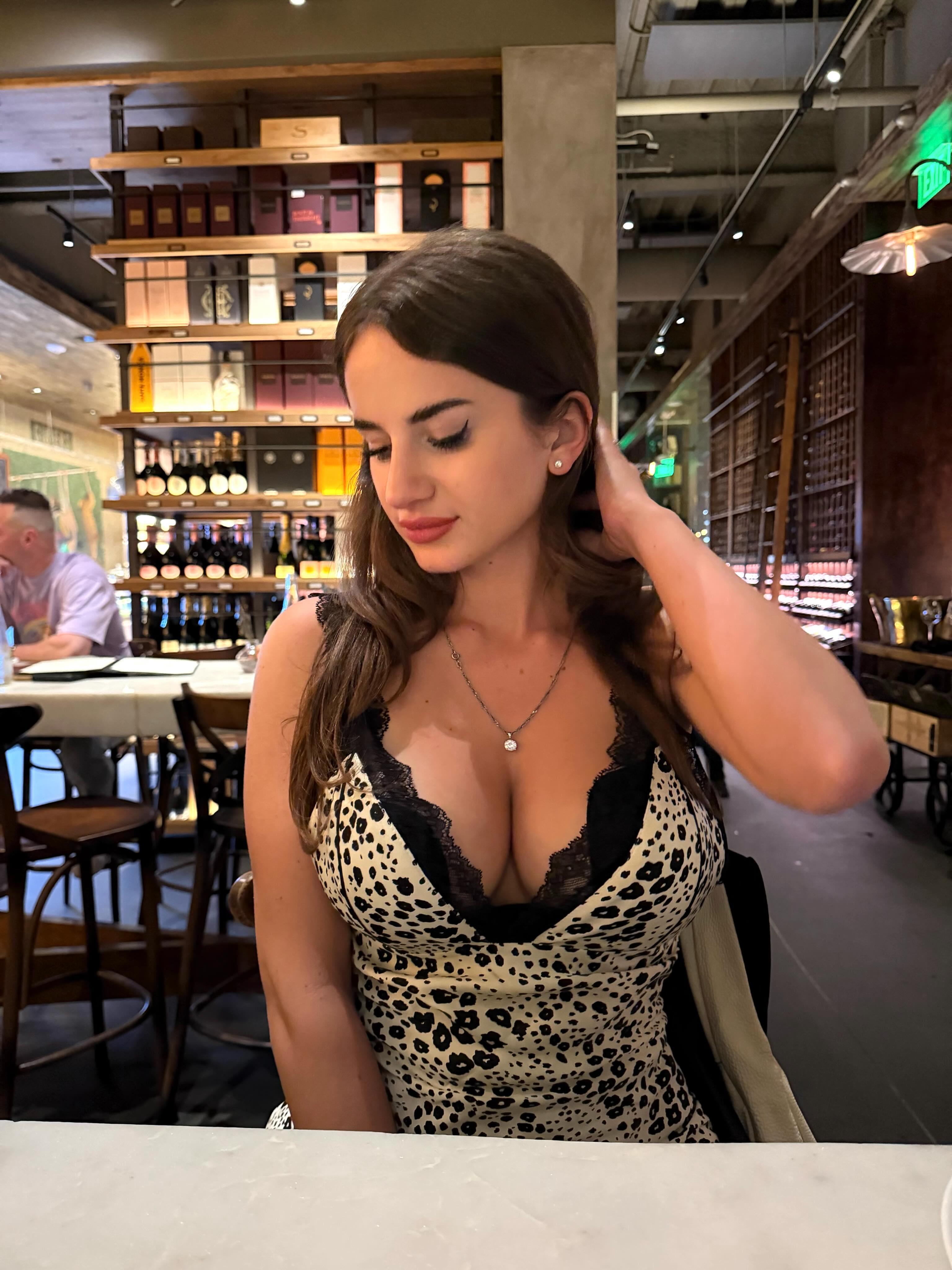 aviebby sitting at a table wearing animal print dress with black lace in restaurant bar
