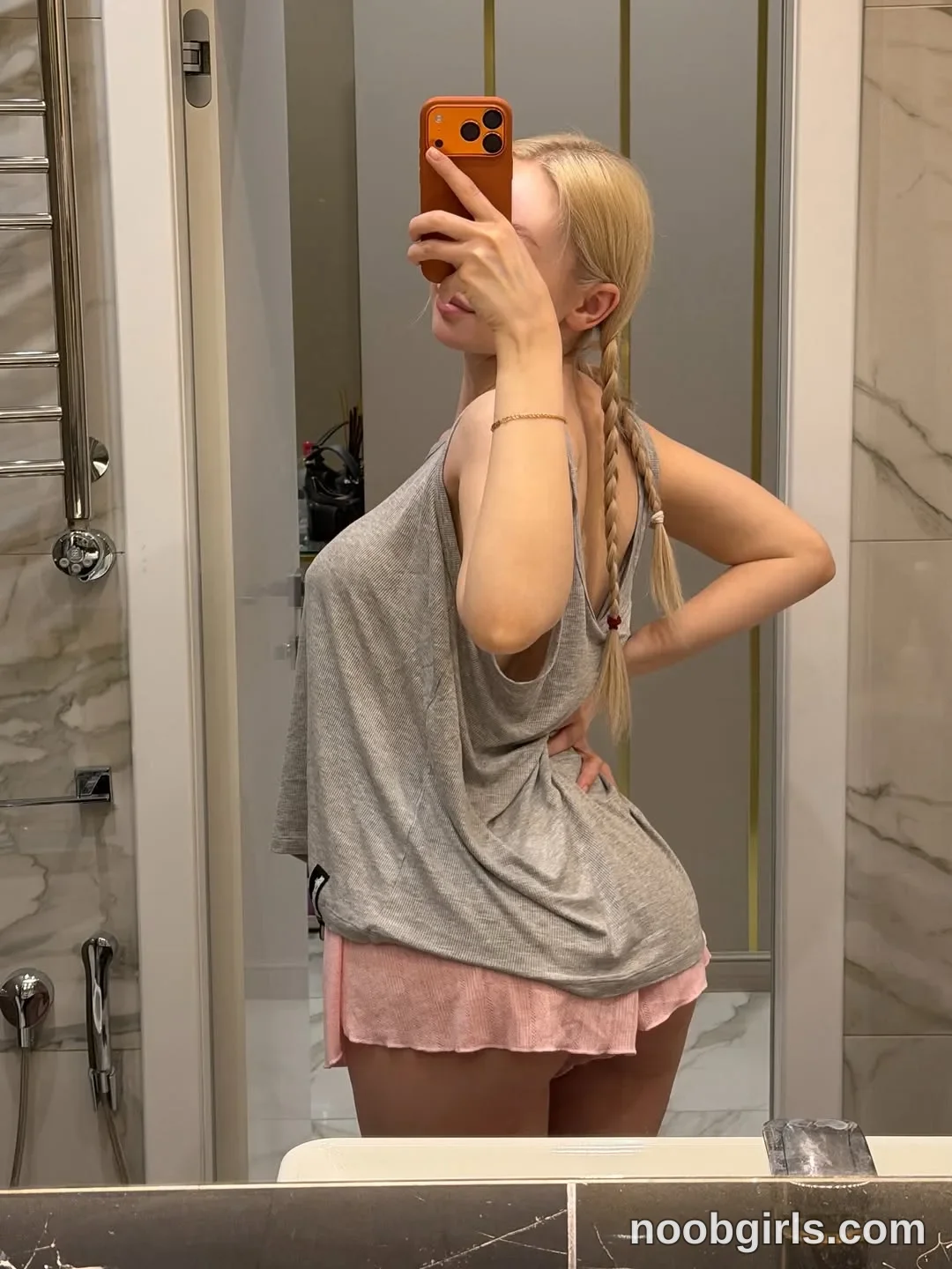 Avrora Standing sideways in front of a mirror wearing Loose grey sleeveless top with deep armholes in bathroom