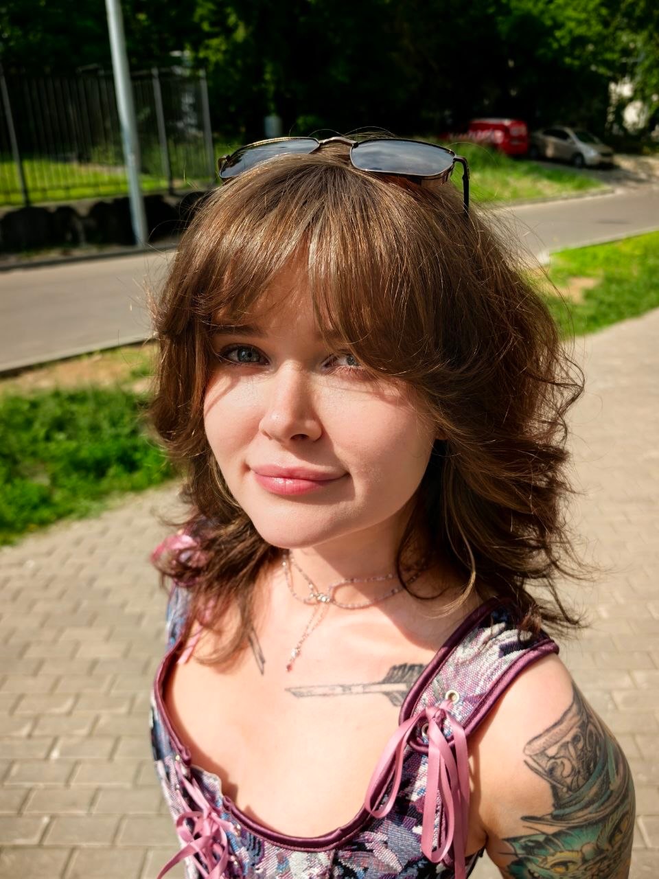 awondrr smiling at camera wearing purple patterned top in sidewalk