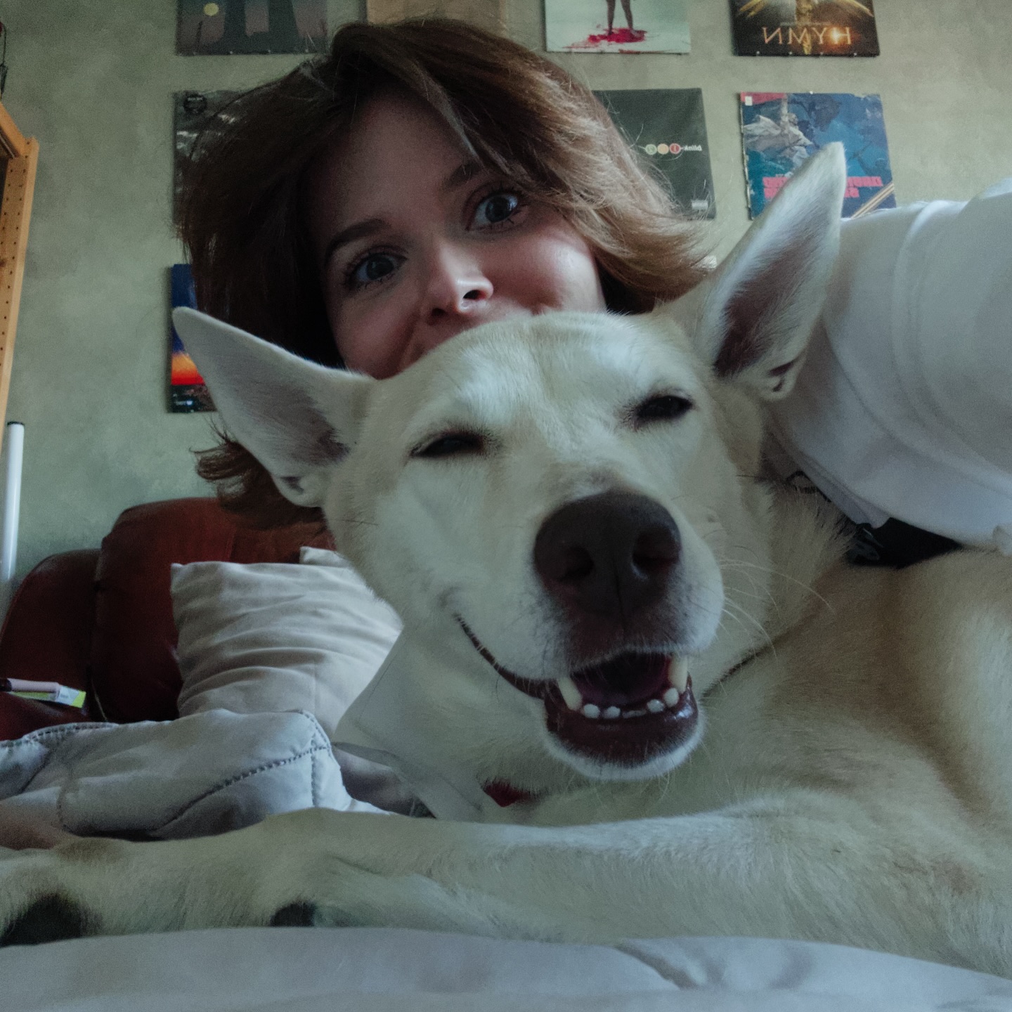 awondrr posing with dog on bed wearing white shirt in room