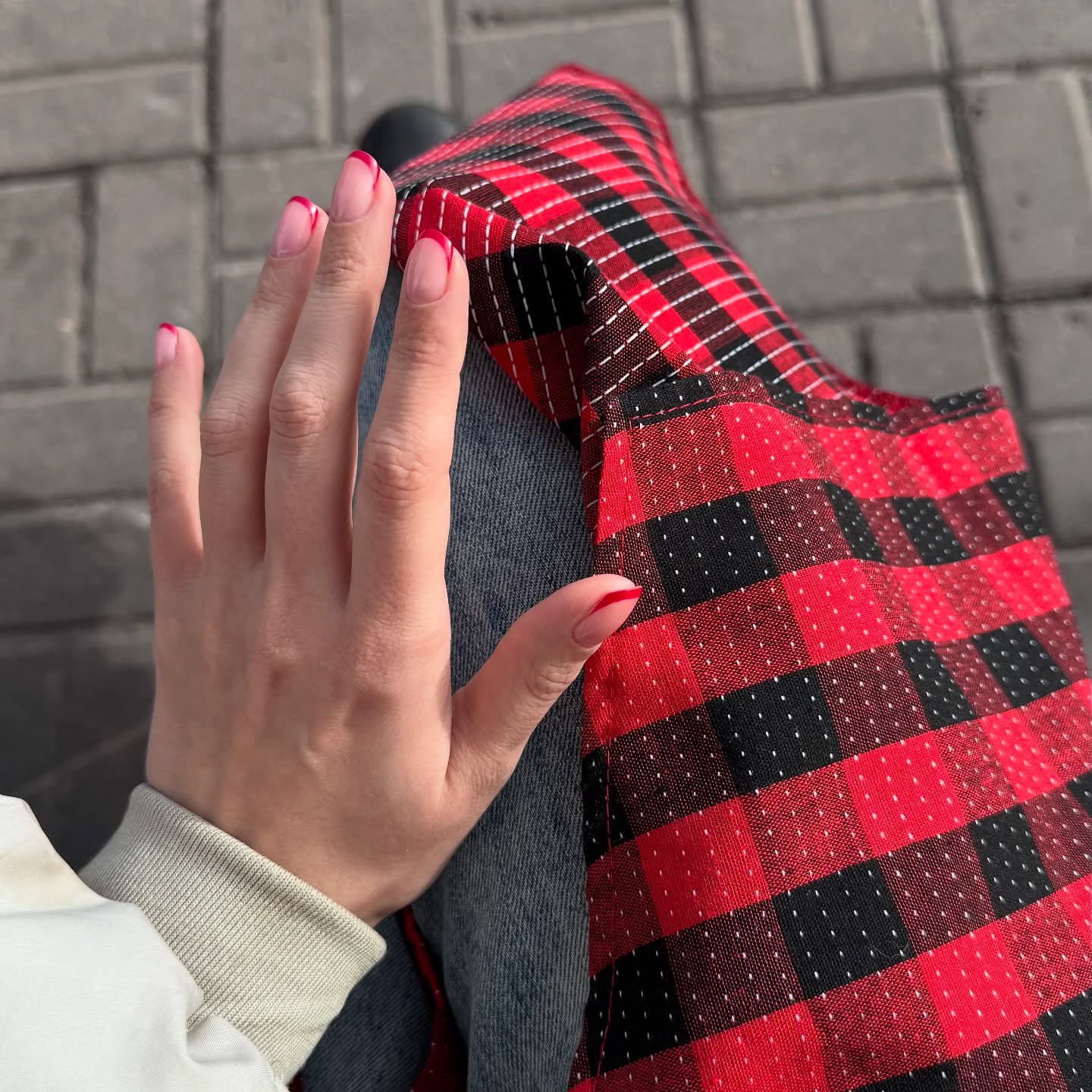 awondrr resting hand on lap wearing blue jeans in paved outdoor walkway
