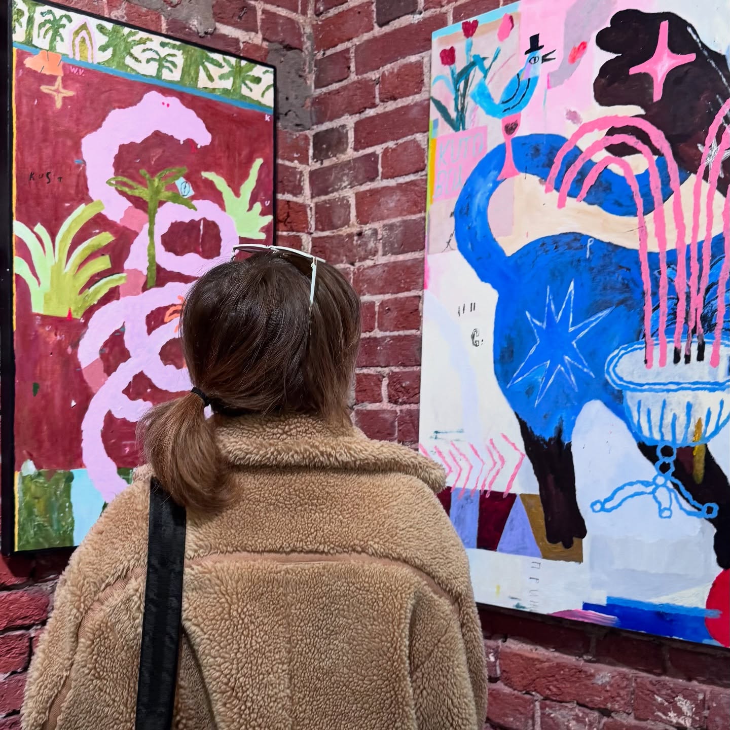 awondrr looking at paintings wearing tan fleece jacket in art gallery