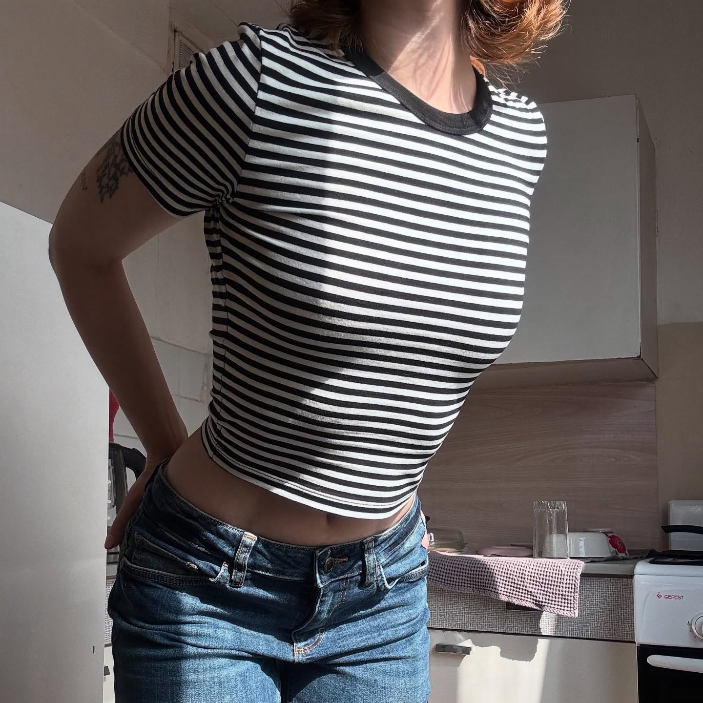 awondrr standing with hands behind back wearing black and white striped t-shirt in kitchen