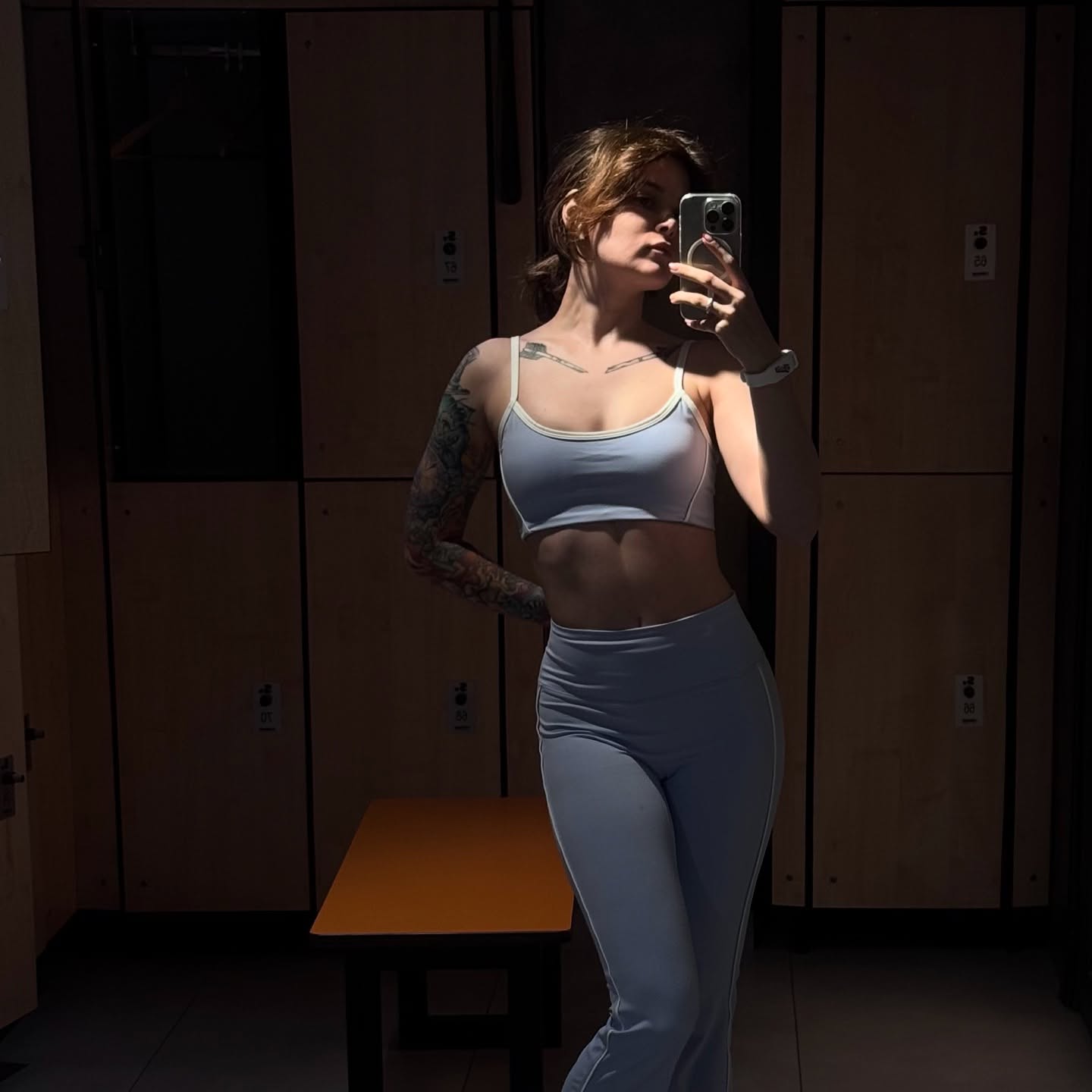 awondrr taking a mirror selfie wearing light blue sports bra in locker room
